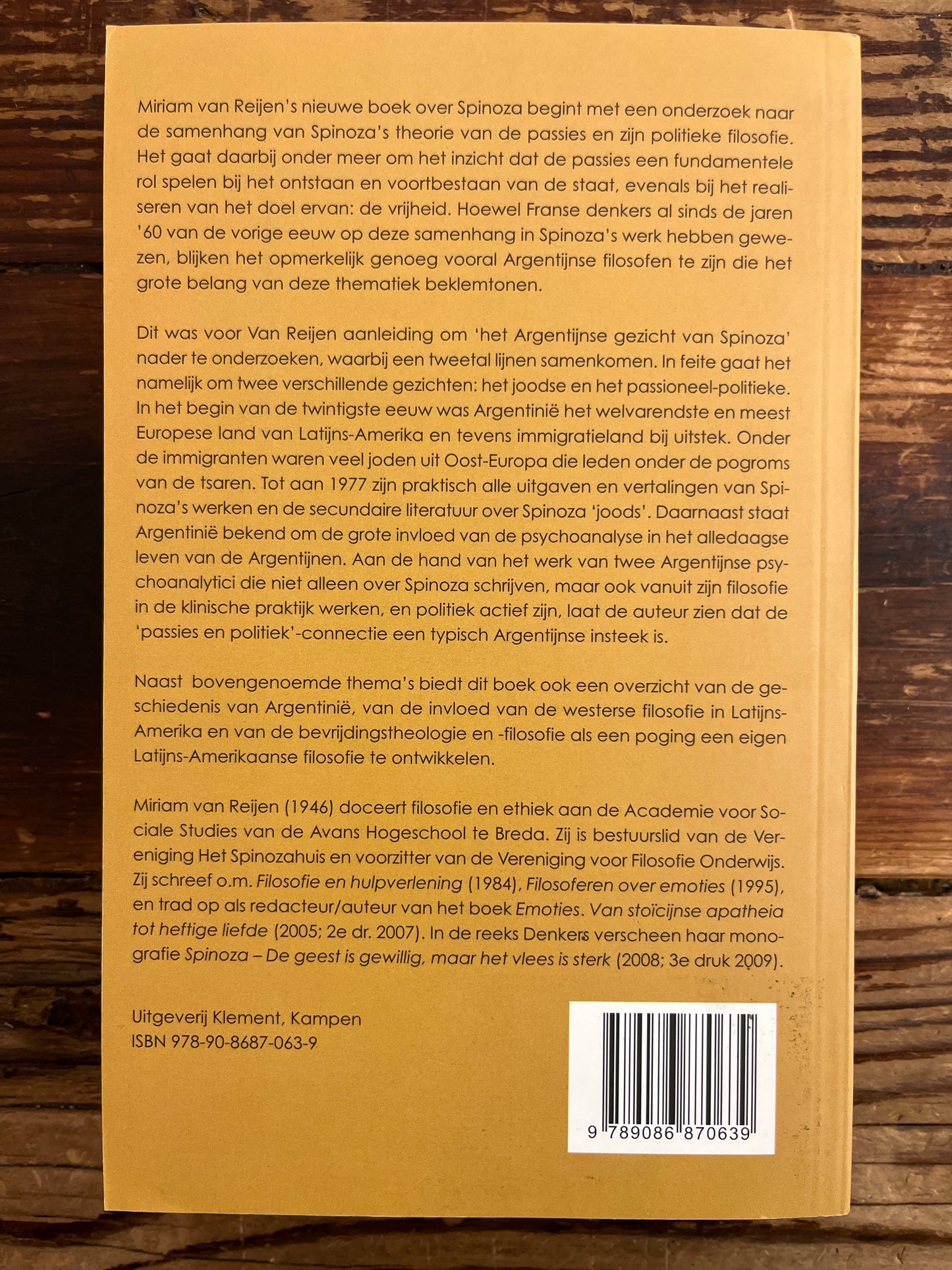 Achterkant boek met de titel 'het Argentijnse gezicht van Spinoza' door Miriam van Reijen op een houten achtergrond
