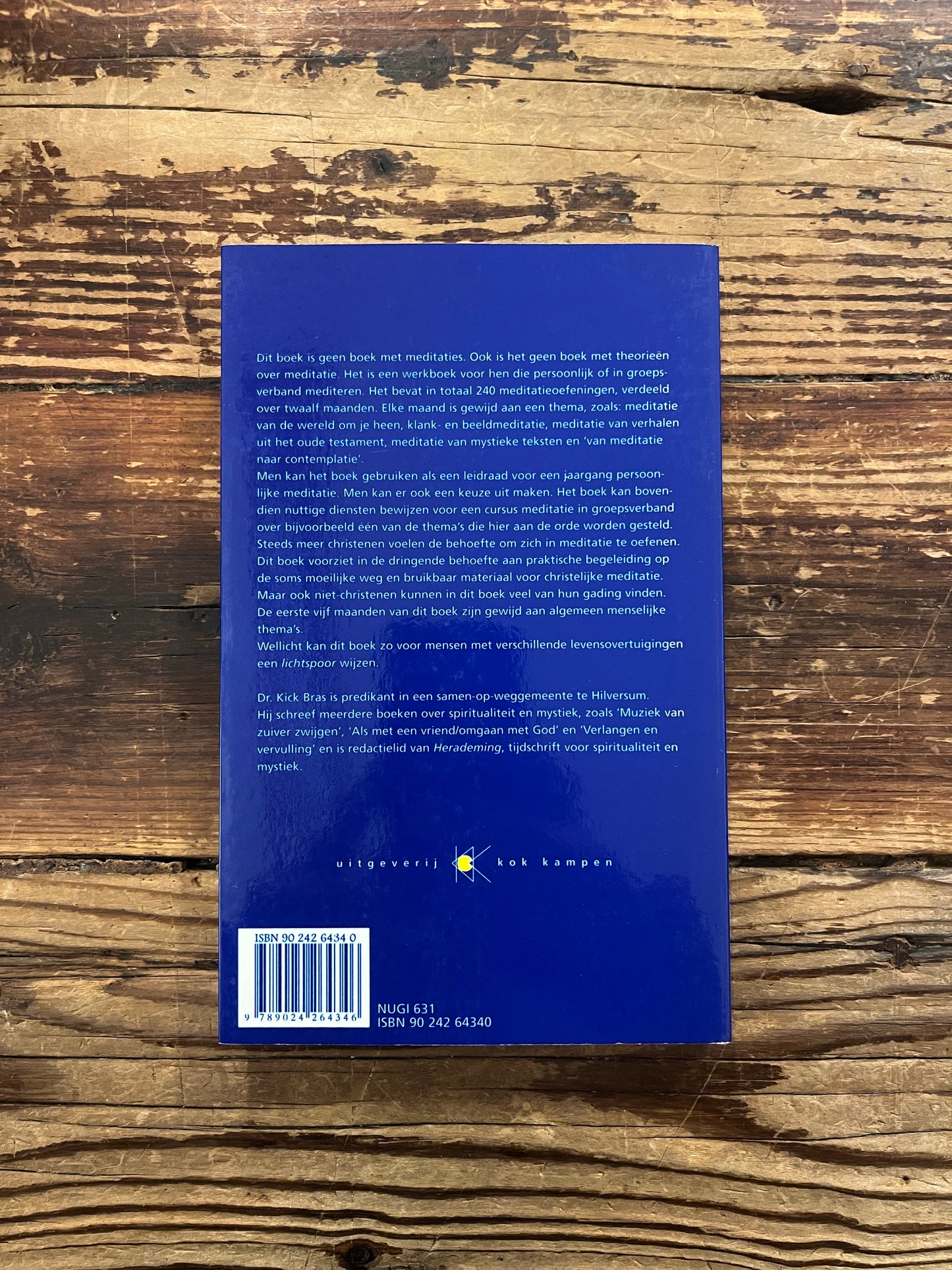 Achterkant van boek 'lichtspoor' door Kick Bras op een houten achtergrond