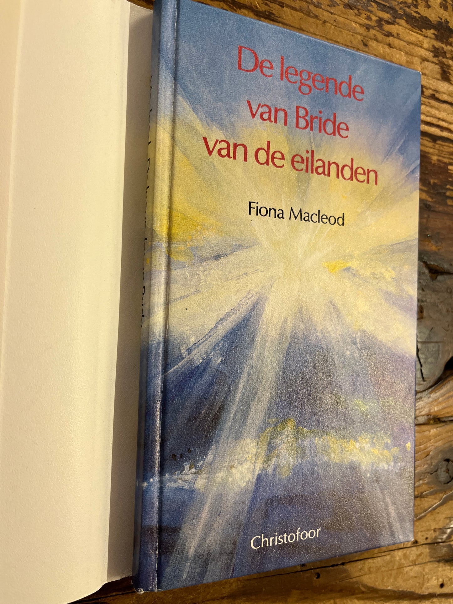 Boek voorkant onder de stof omslag met titel 'De legende van Bride van de eilanden' door Fiona Macleod op houten achtergrond
