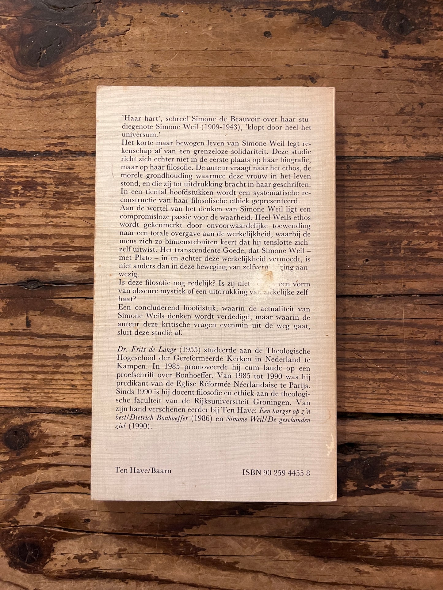 Foto van de omslag van het boek "het ehtos van simone weil" op houten achtergrond