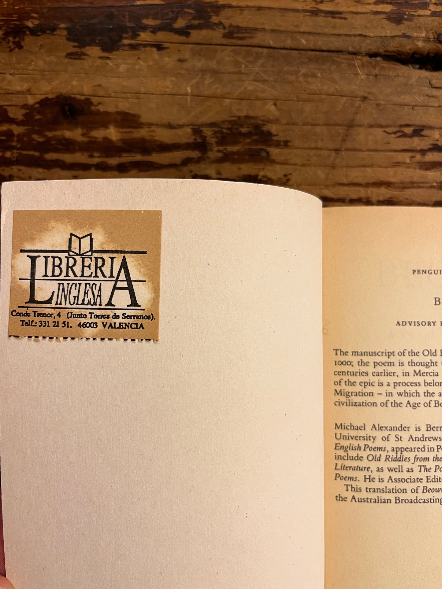 Open book on a wooden surface with a visible Libreria Lincenza sticker on the inside of the front cover
