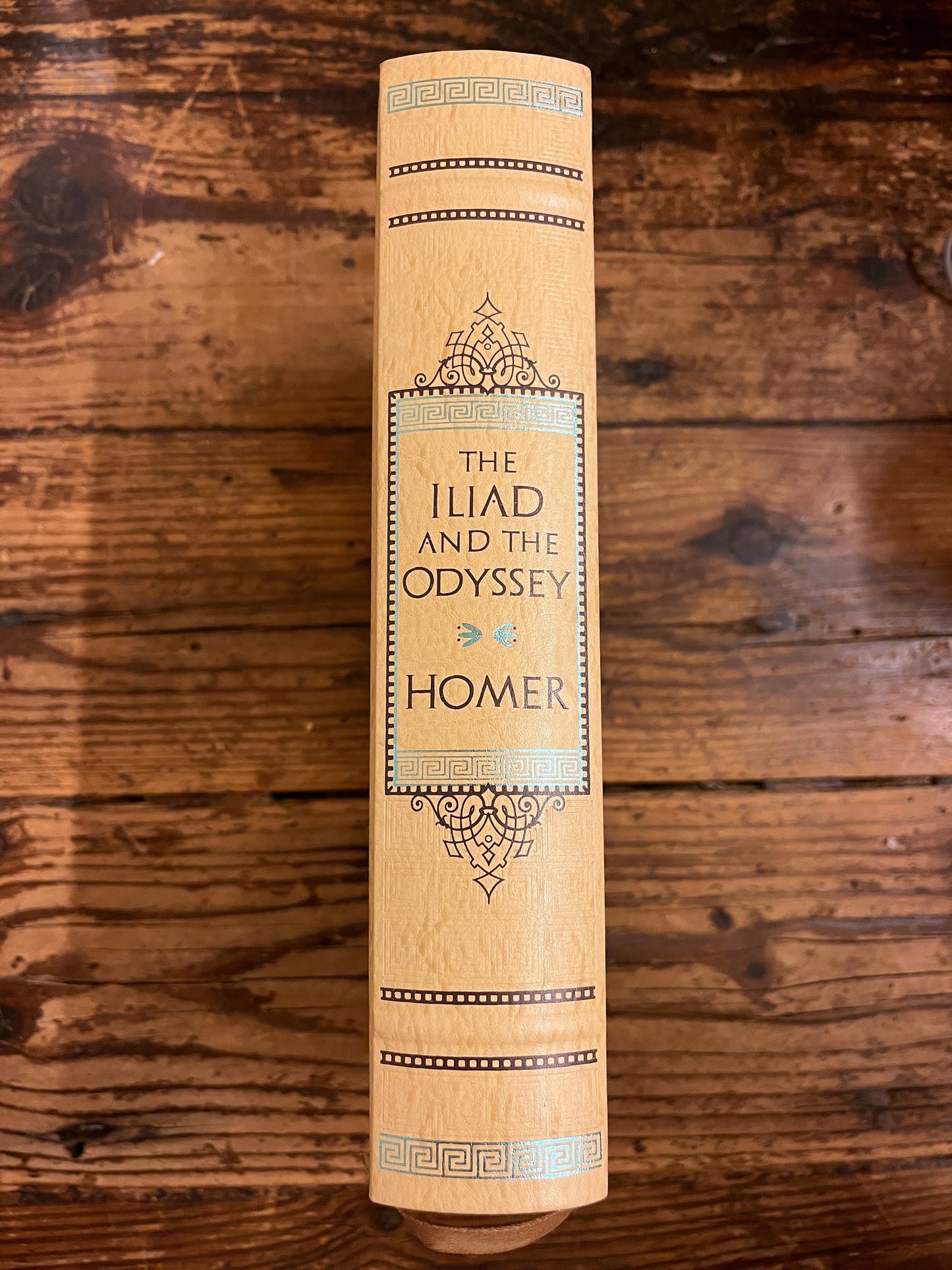 photo of the spine of the book "the iliad and the odyssey"on a wooden background