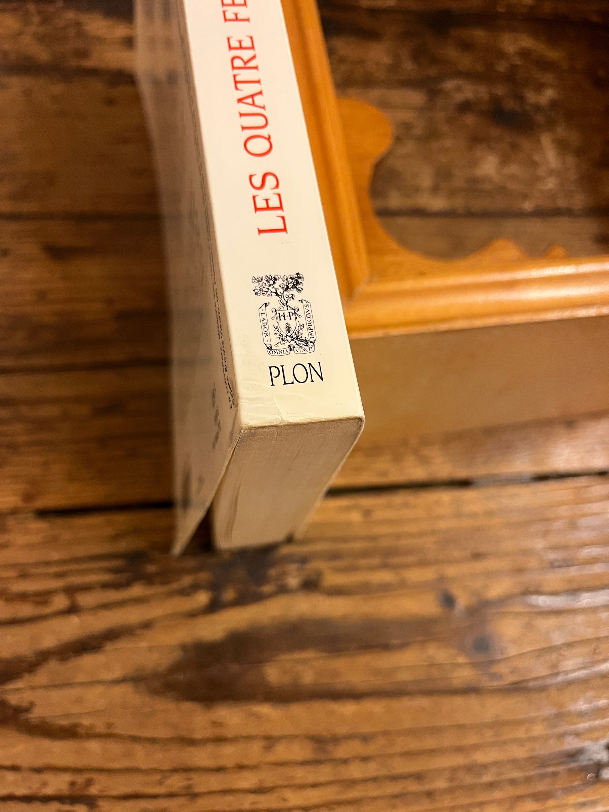 détail d'une imperfection du livre "les quatres femmes de dieu" au bas du dos. celui ci est legerement enfonce. sur fond de bois