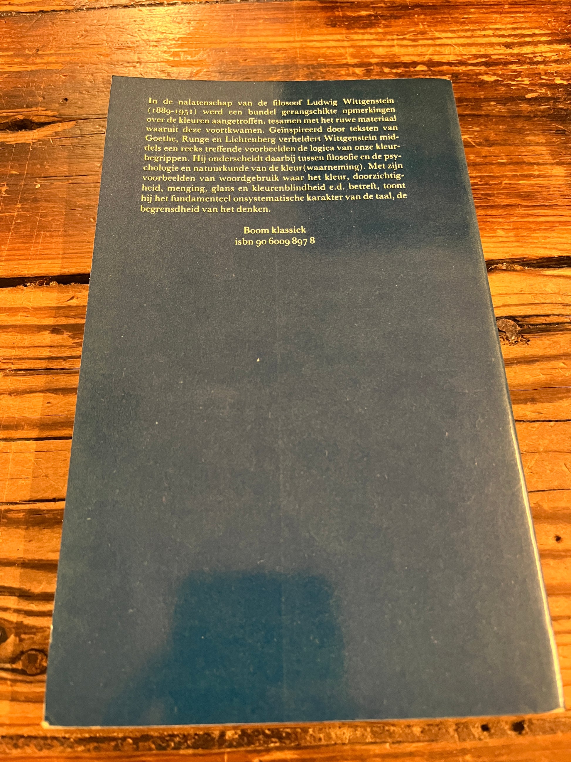 Achterkant van boek met de titel 'opmerkingen over de kleuren' door Wittgenstein op houten achtergrond