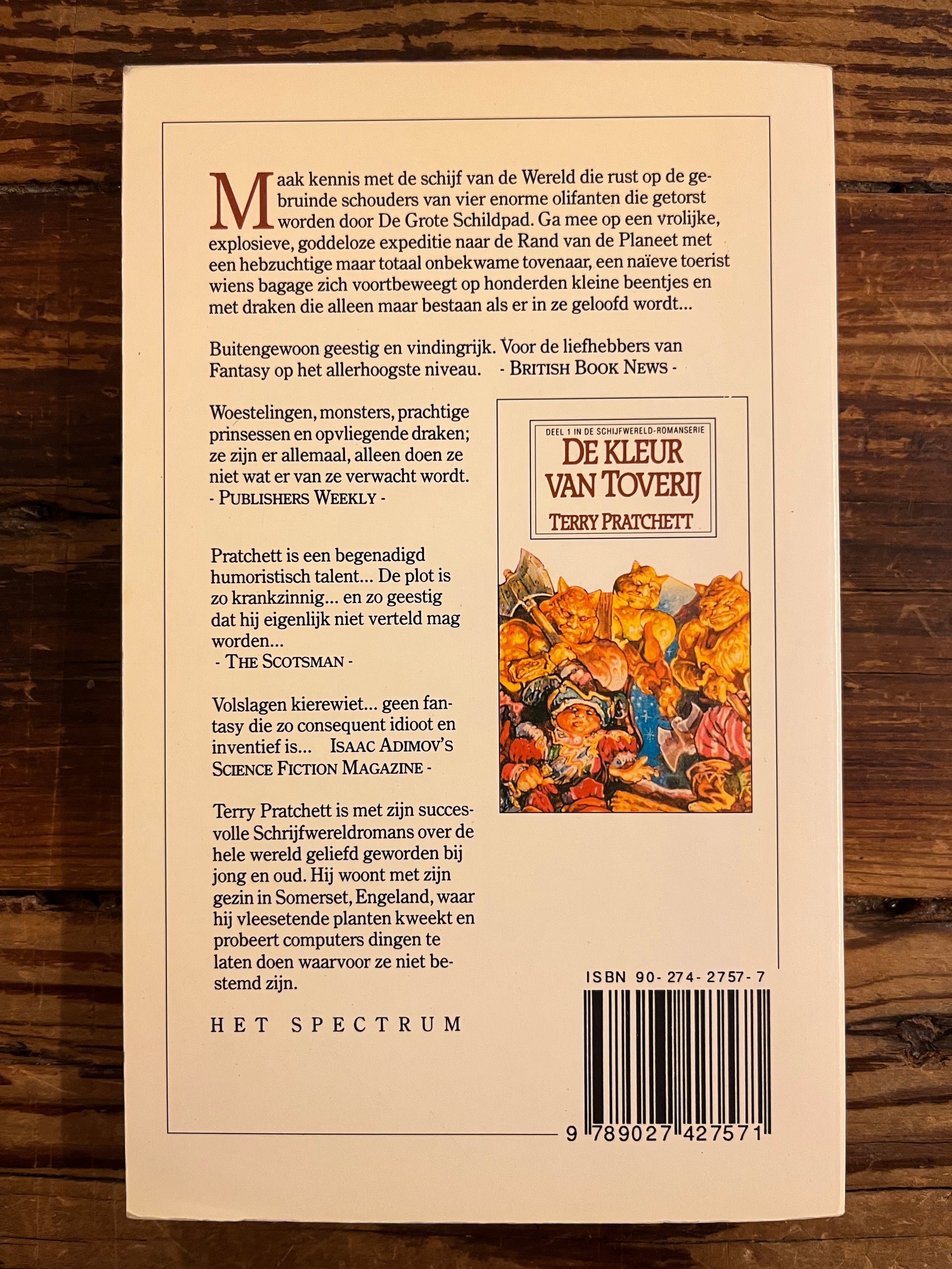 Achterkant boek met de titel 'de kleur van Toverij' door Terry Prachett op houten achtergrond