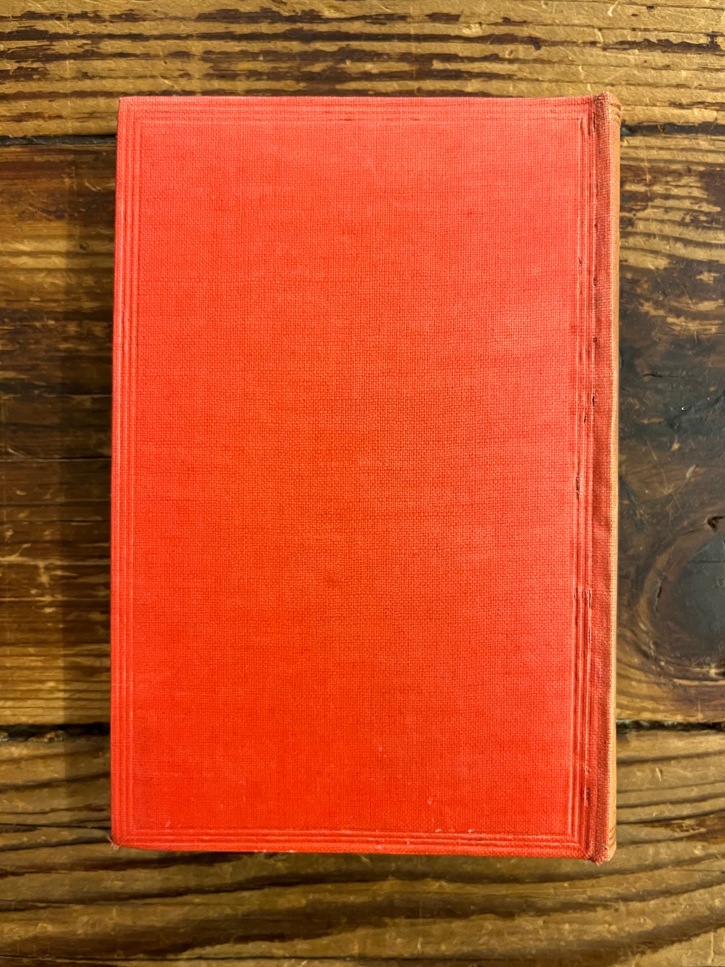 Back cover of a 1922 macmillan & co miniature edition of 'Alice's adventures in wonderland' by Lewis Carroll on a wooden surface