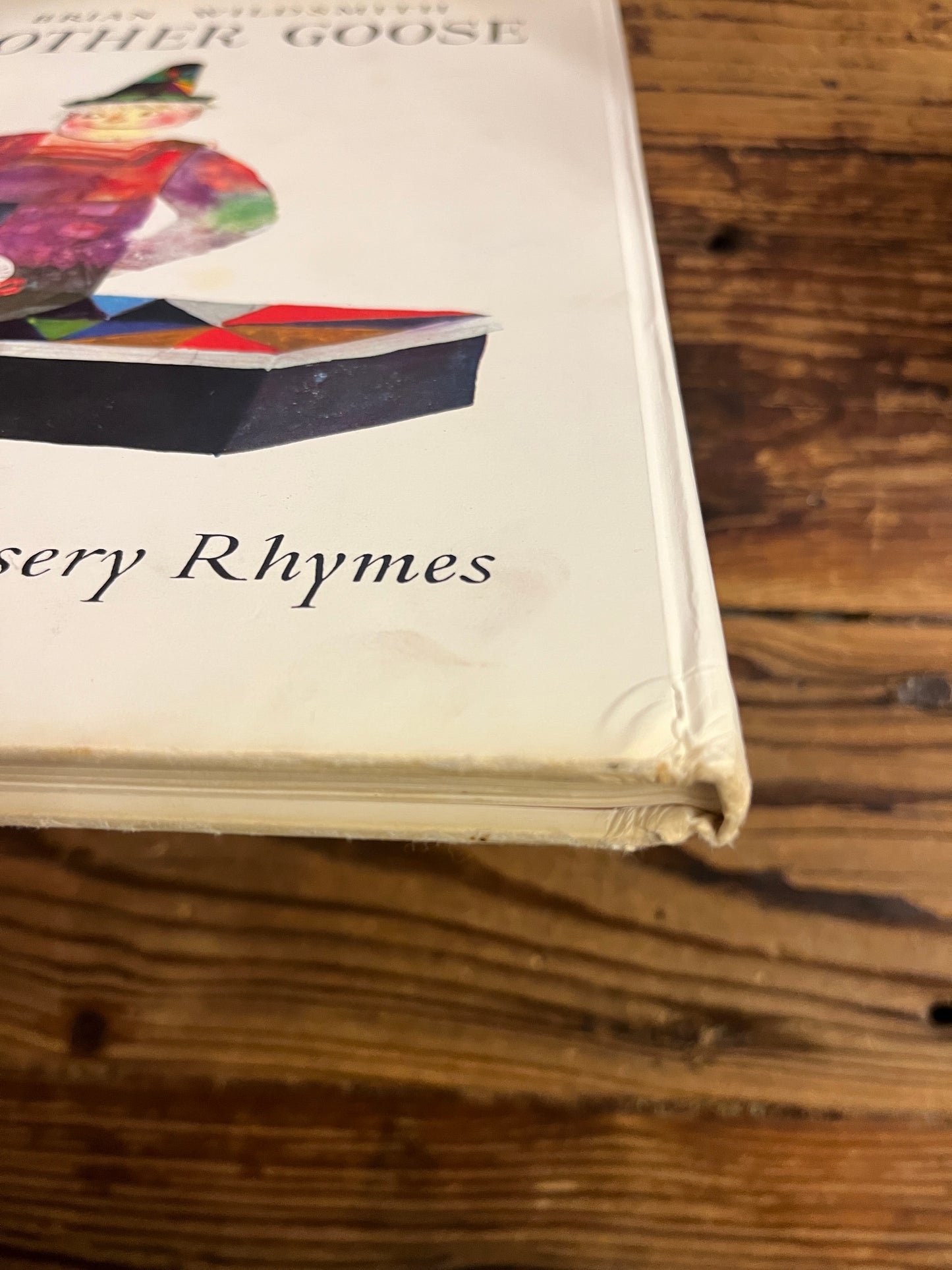 Showing a light bump on the spine of a book titled 'Mother Goose' by Brian Wild Smith on a wooden surface