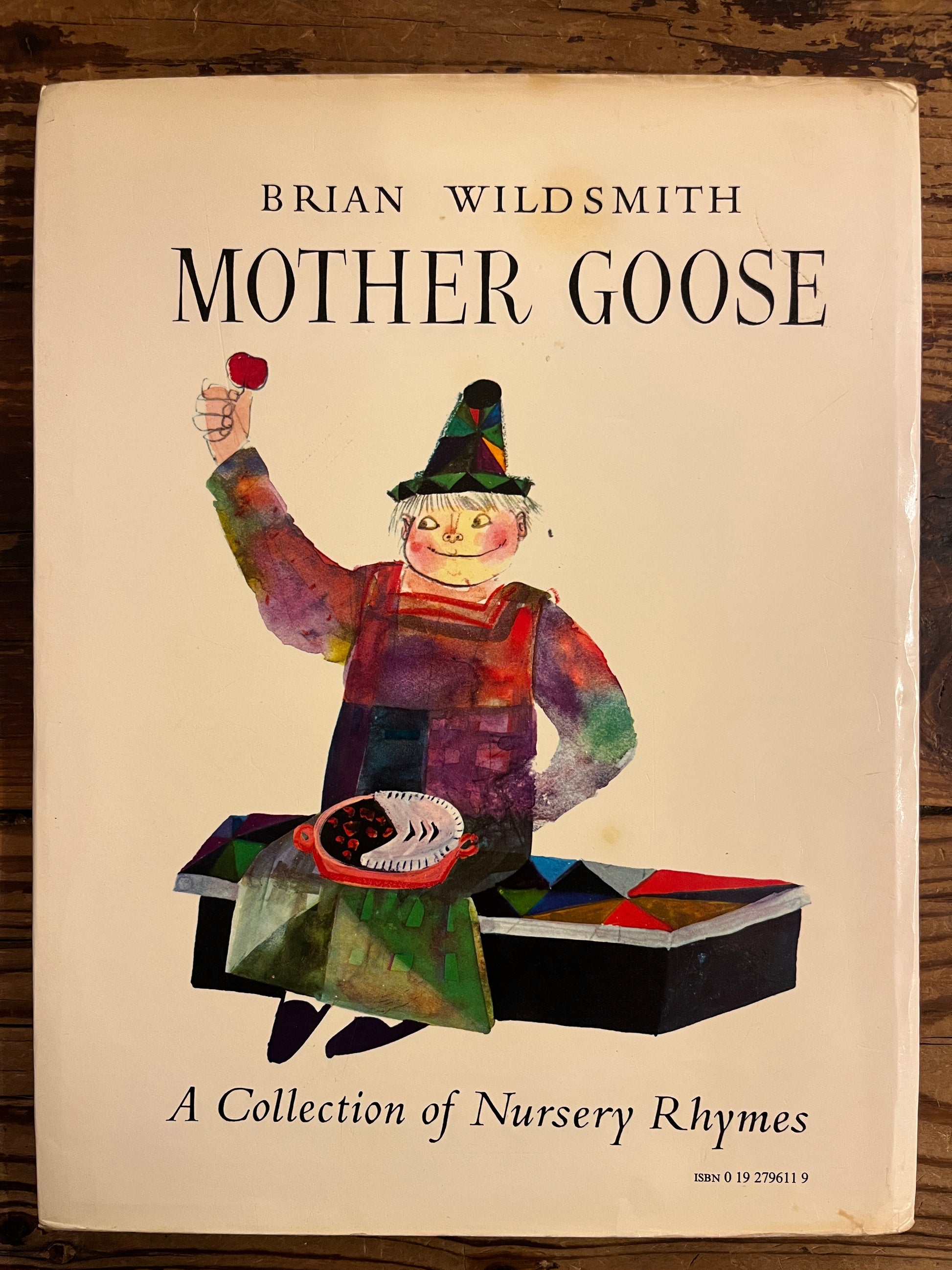 Back cover with dust-jacket of ook titled 'Mother Goose' by Brian Wild Smith on a wooden surface