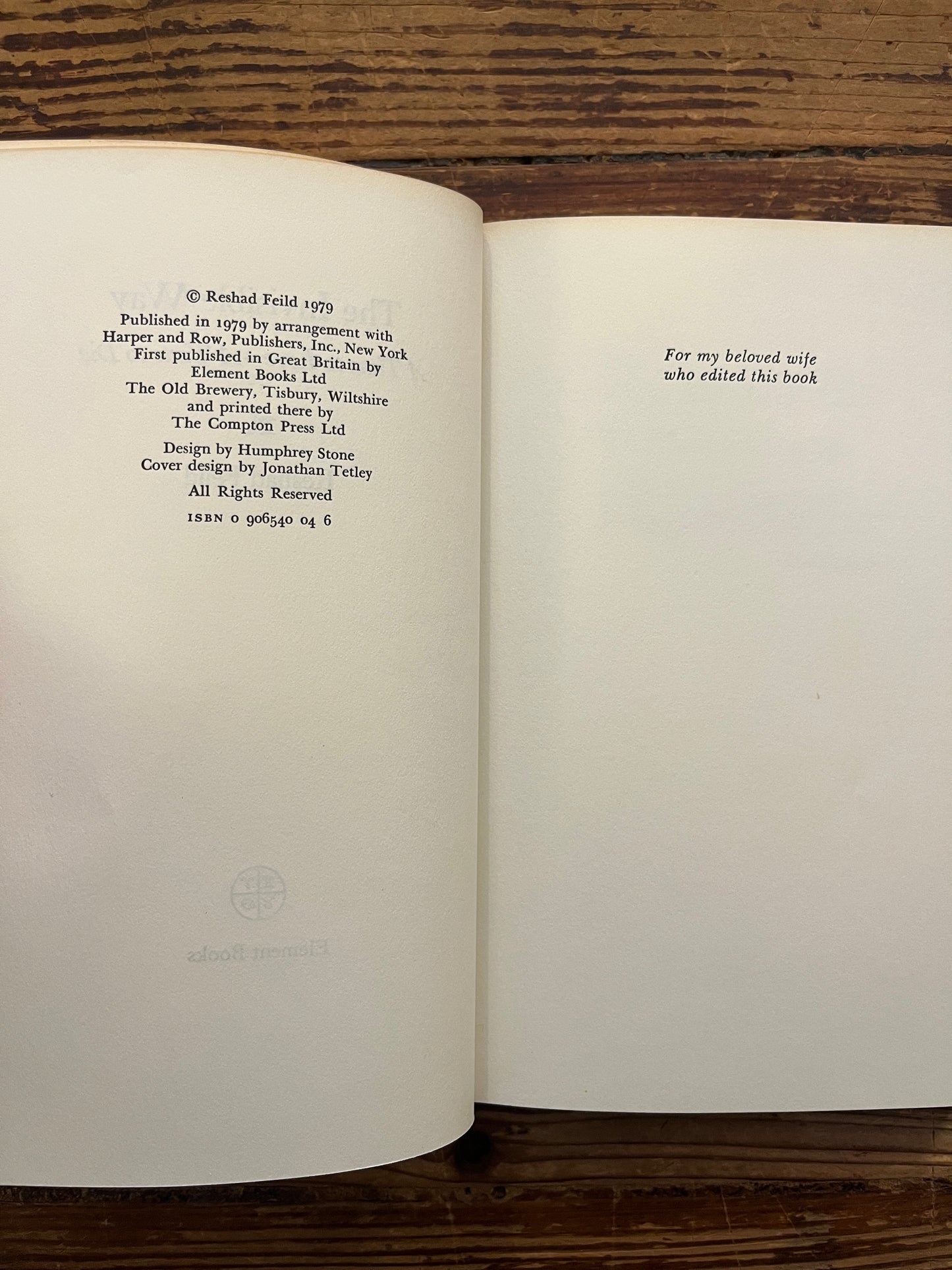 Open book with the title 'the invisible way' by Reshad Feild on a wooden surface