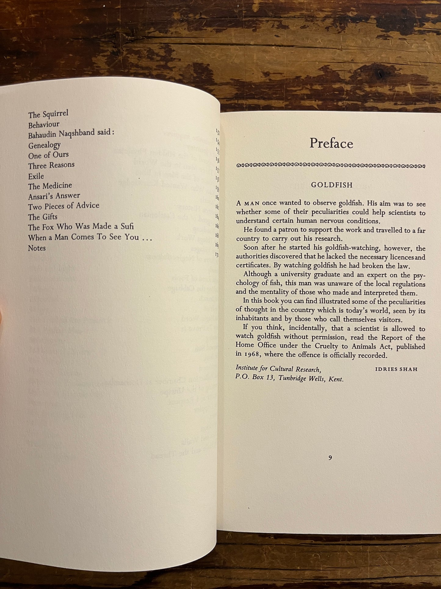 Open book 'The Dernis Probe' by Idries Shah with text on a wooden surface