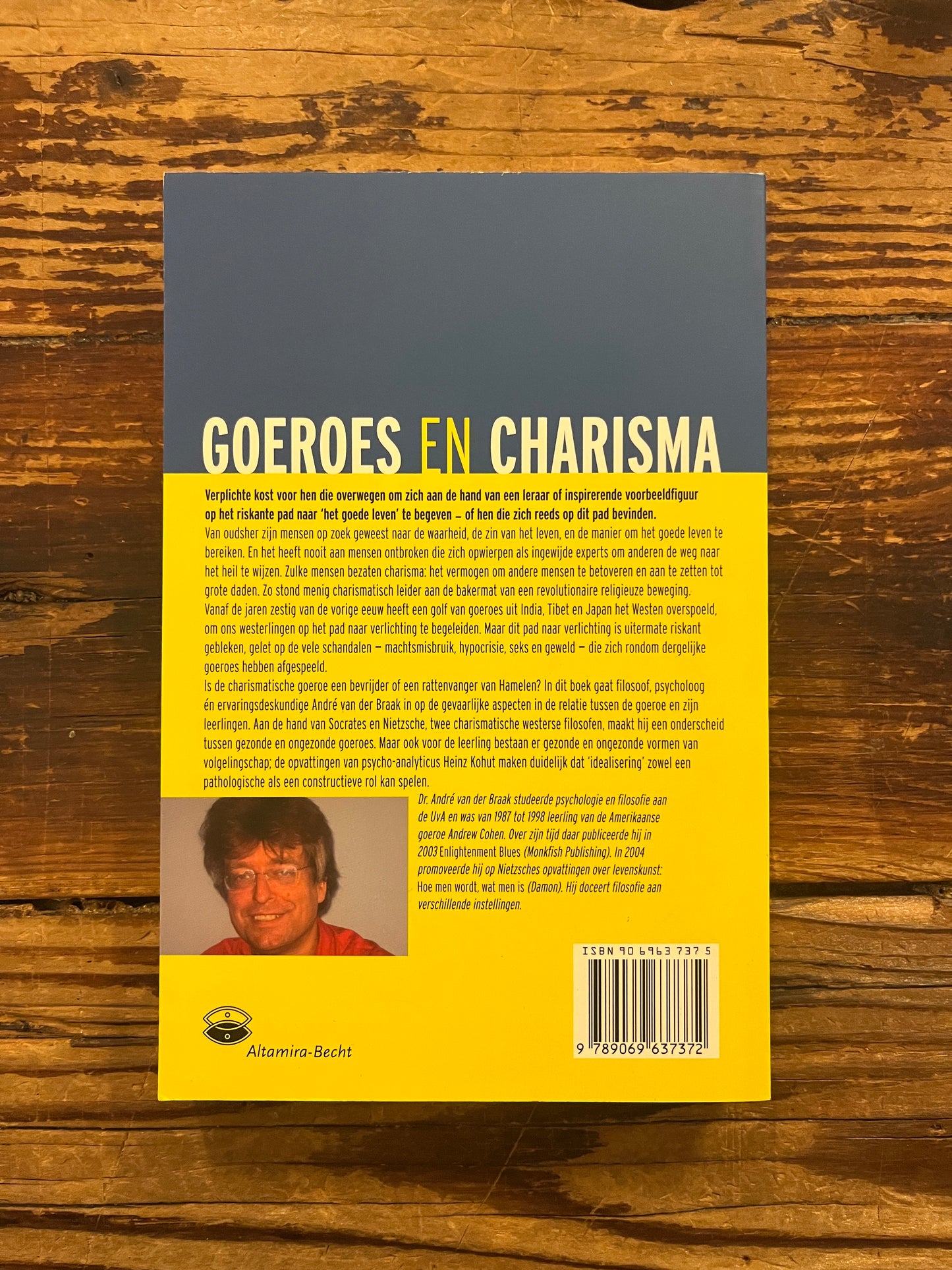 Achterkant van boek 'goeroes en charisma' door André van der Braak op een houten achtergrond