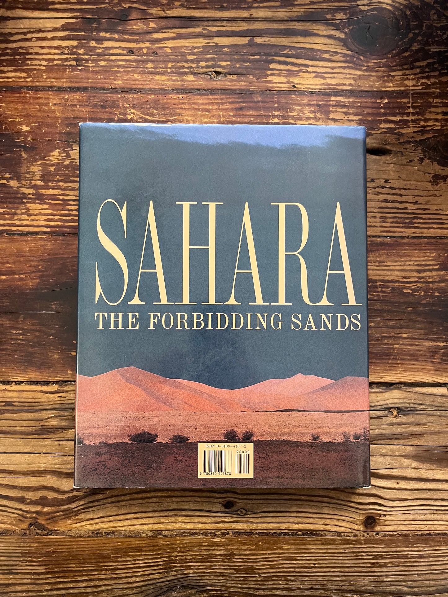 Back cover of book titled 'Sahara: The Forbidding Sands' by Jean-Marc Durou on a wooden surface