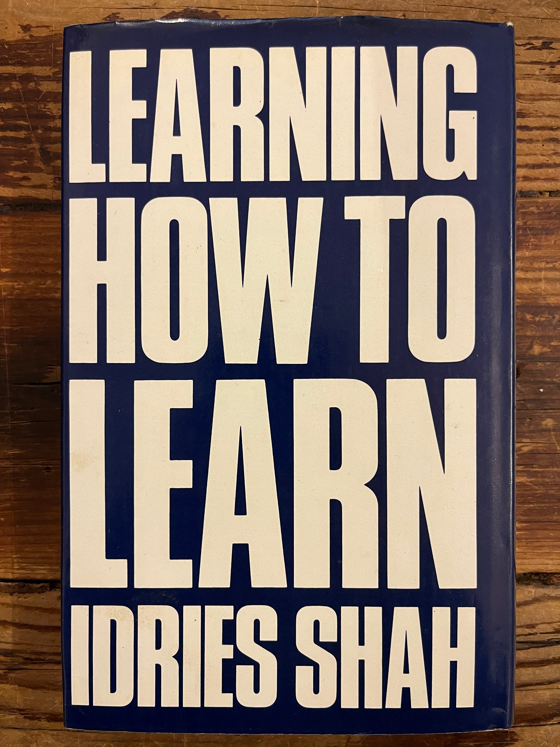 Back cover of book titled 'Learning How to Learn' by Dries Shah on a wooden surface