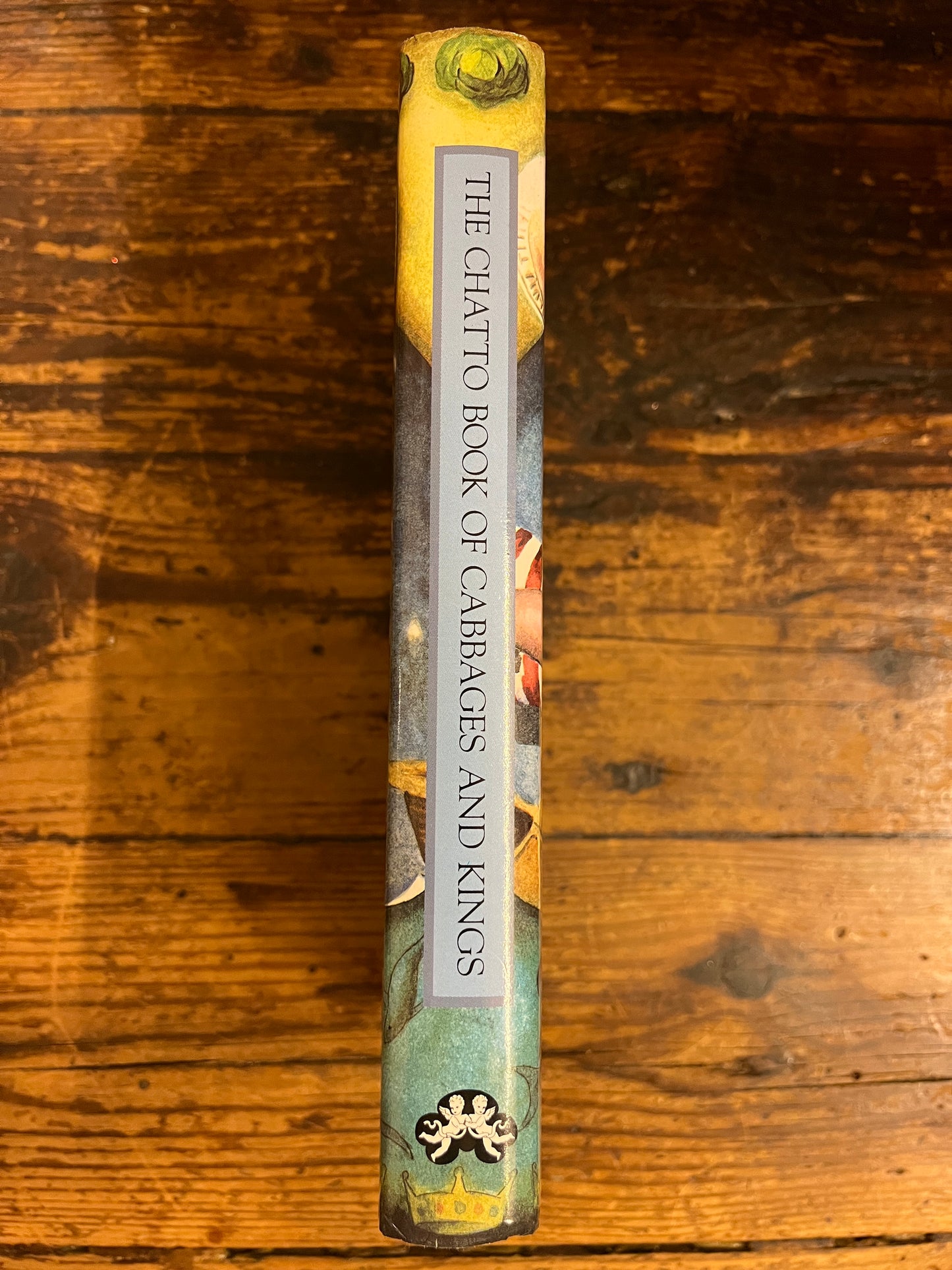 spine of the book "The chatto book of cabbages and kings"on a wooden background