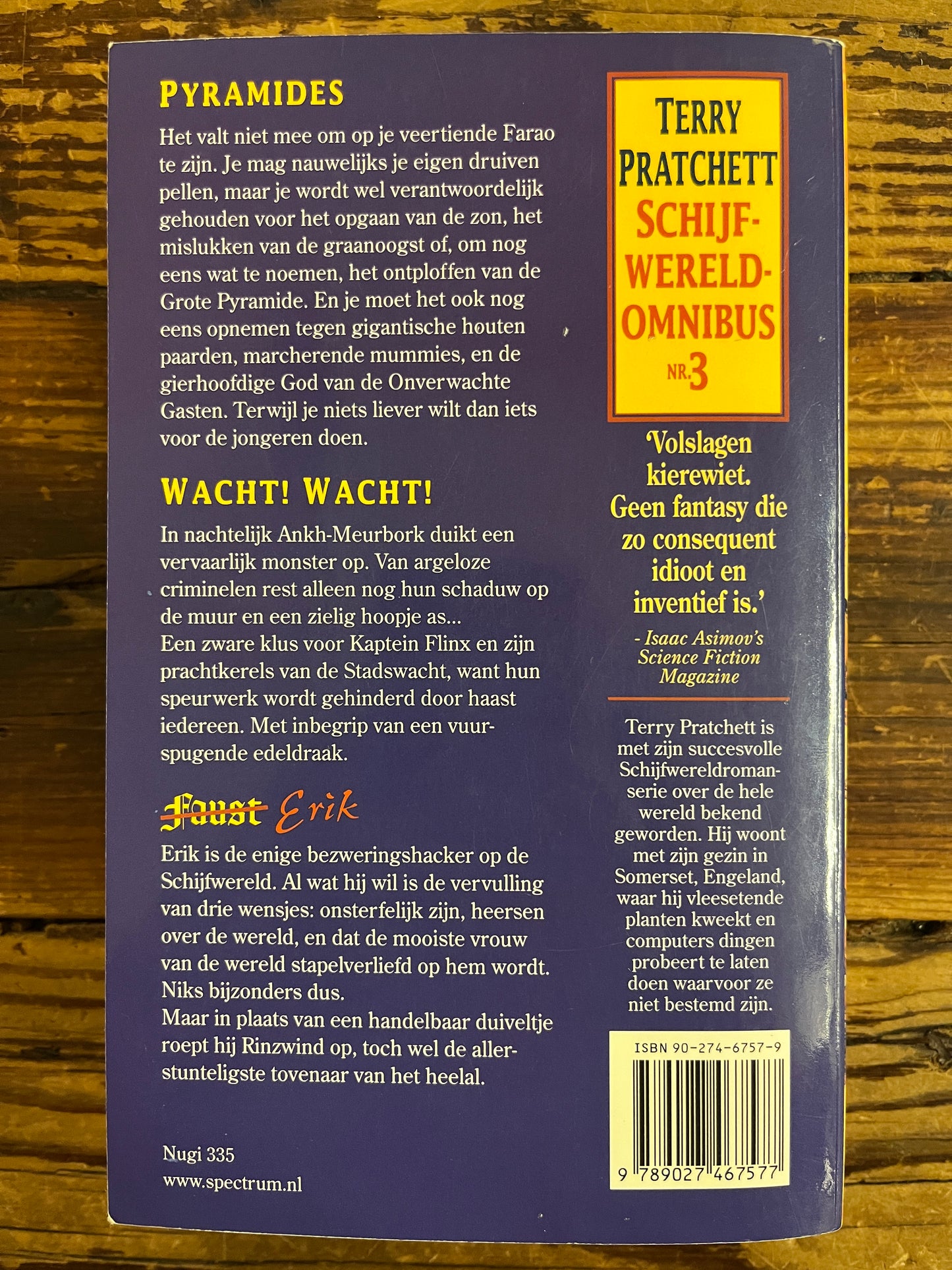 Achterkant van boek met de titel 'Terry Pratchett Schijfwereld Omnibus n 3' op een houten achtergrond