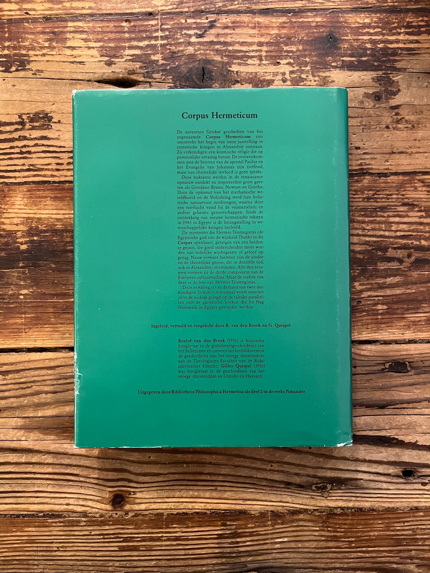 Achterkant van boek 'Corpus hermeticum' ingeleid, vertaald en toegelicht door R. van den Broek en G. Quispel, op een houten achtergrond
