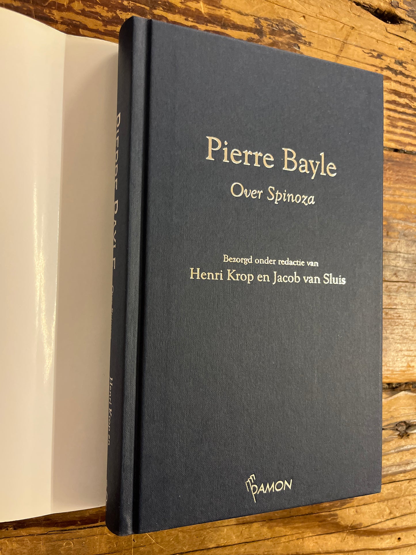 hardcover boek met de titel 'Pierre Bayle over Spinoza' op een houten achtergrond