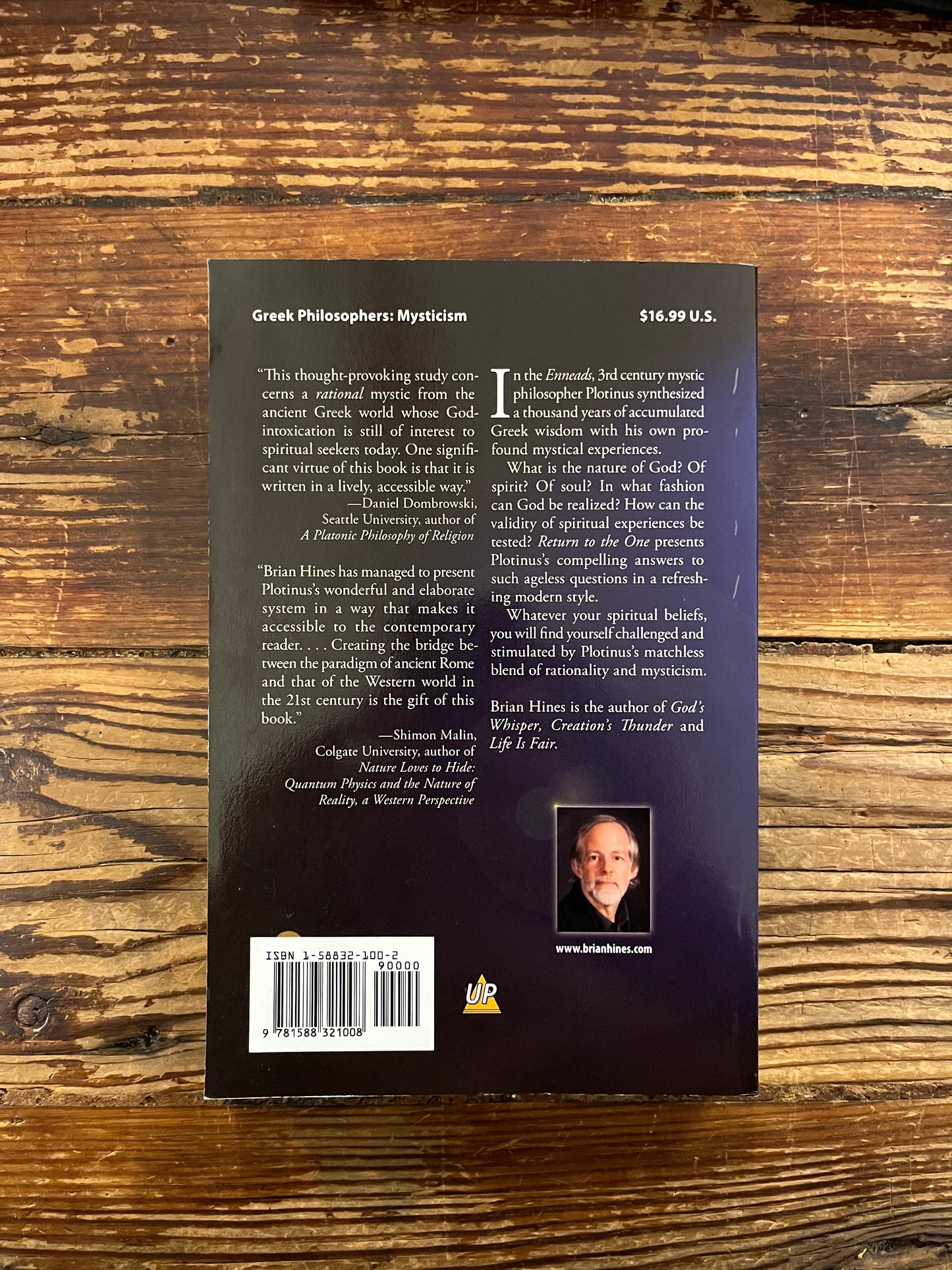 Open book titled 'Return to the One, Plotinus guide to God-Realization' by Brian Hines on a wooden surface