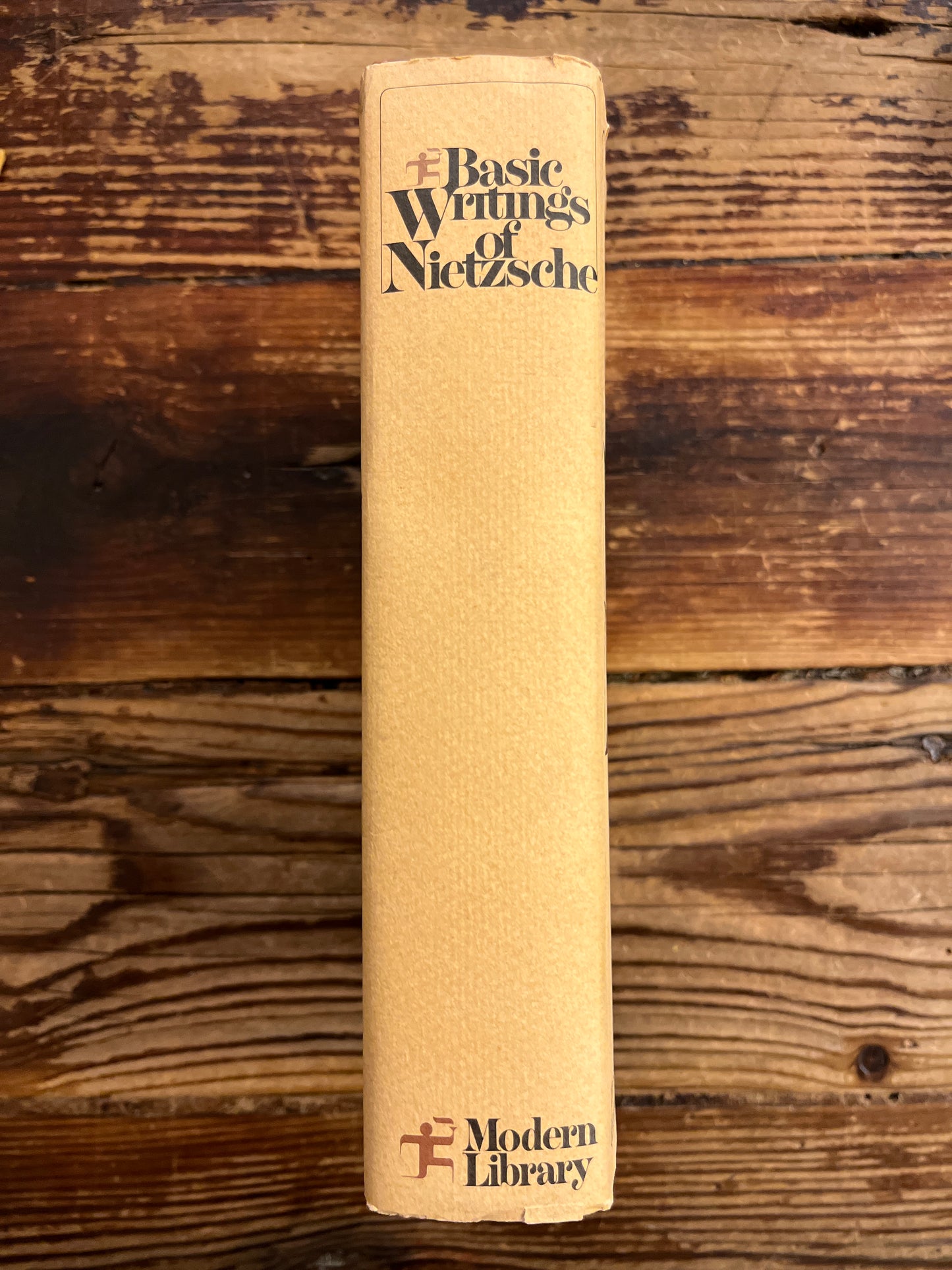 Spine of book titled 'The Basic Writings of Nietzsche' on a wooden surface