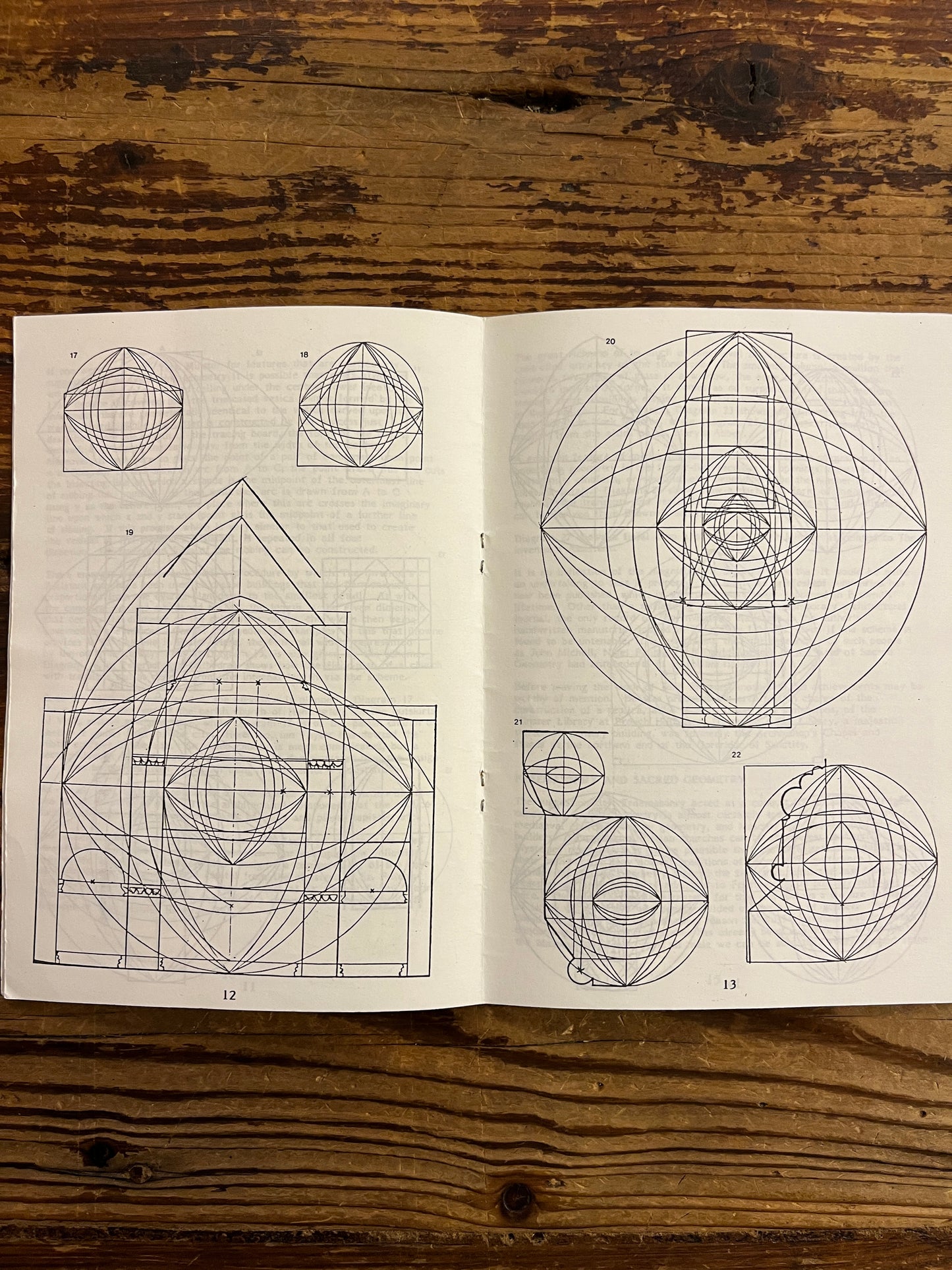Open book with geometric drawings on a wooden surface
