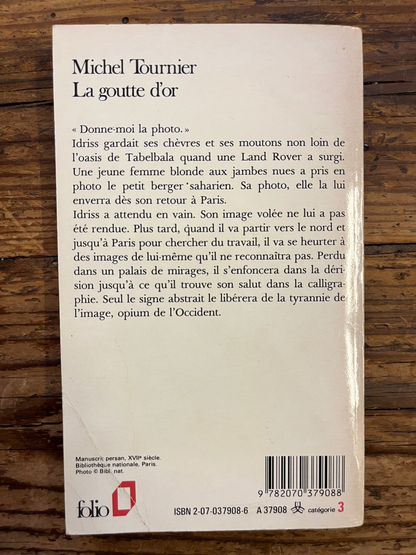 dos du livre "la goutte d'or" de Michel Tournier aux editions Folio sur fond de bois