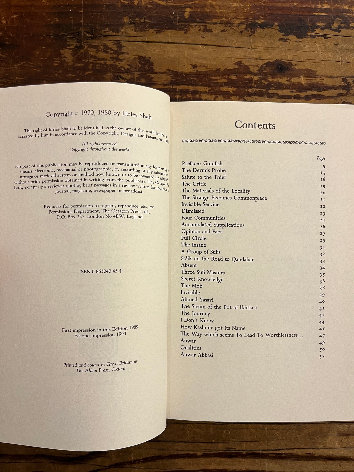Open book 'The Dernis Probe' by Idries Shah with a wooden background