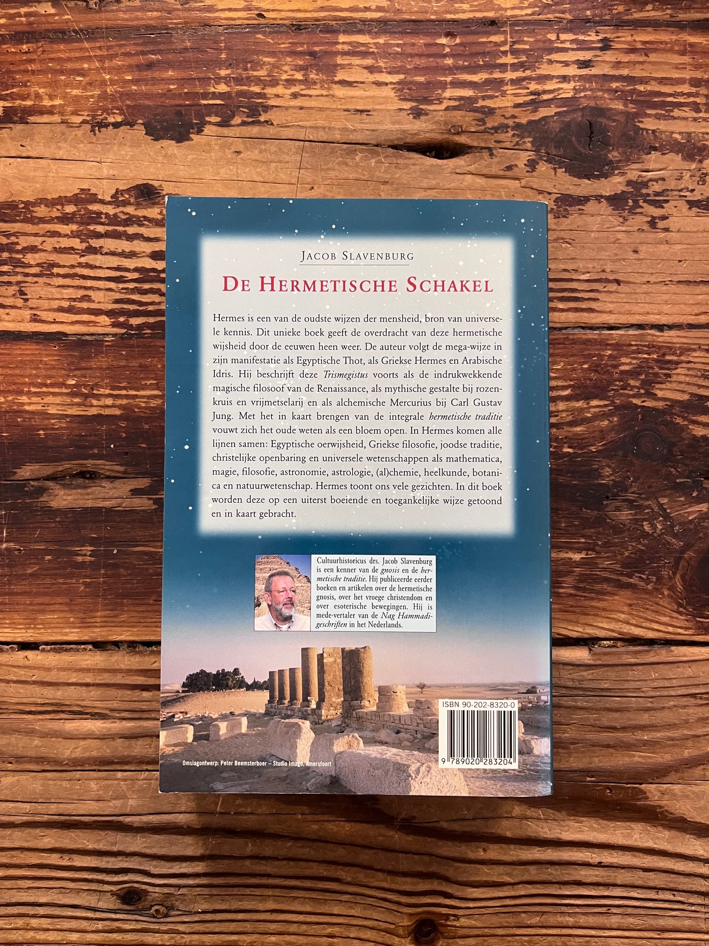 Achterkant van boek met de titel 'de Hermetische Schakel' door Jacob Slavenburg op een houten achtergrond