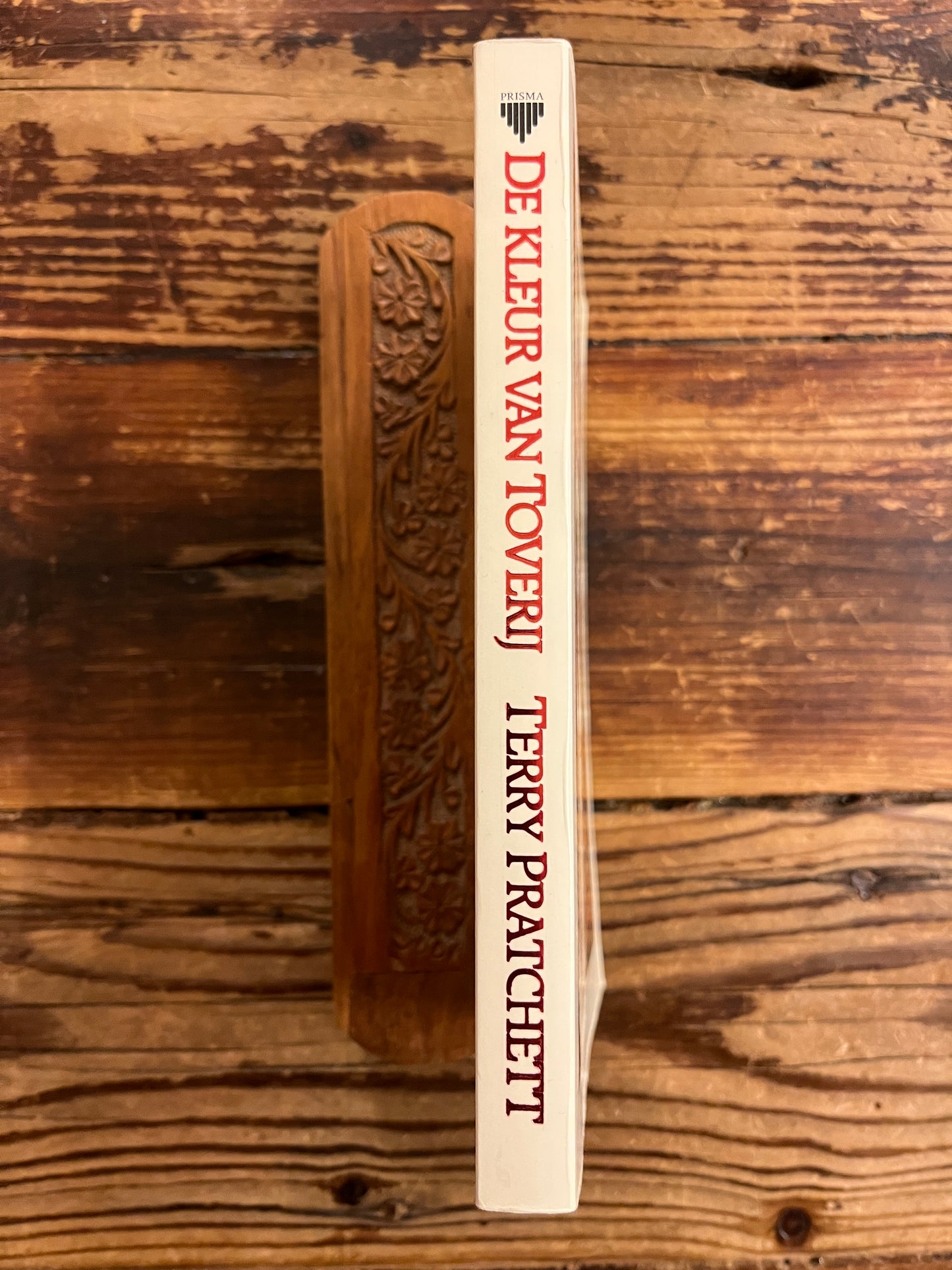 rug van boek met de titel 'de kleur van Toverij' door Terry Prachett op een houten achtergrond