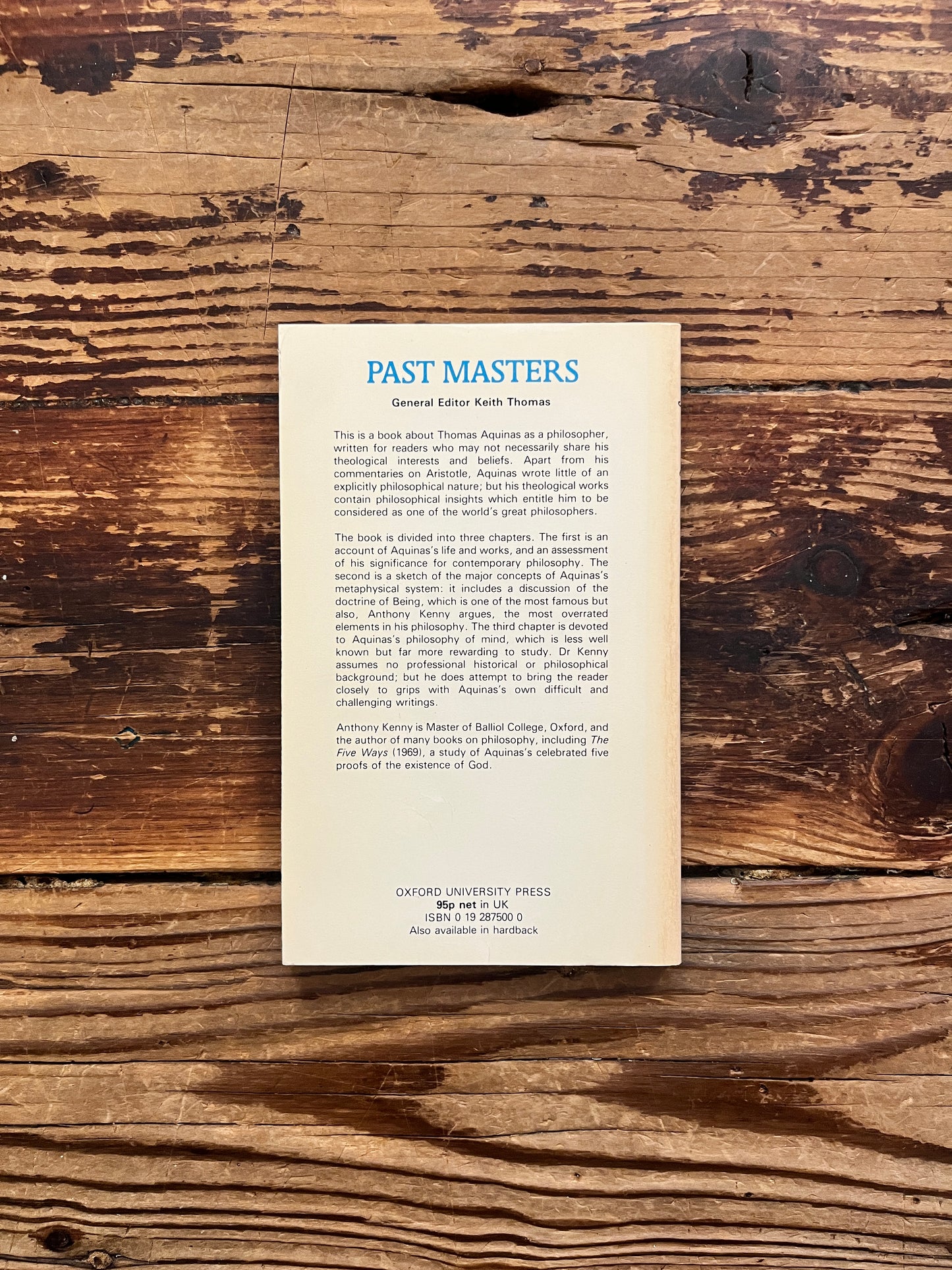 Back cover of book titled 'Aquinas by Anthony Kenny on a wooden surface