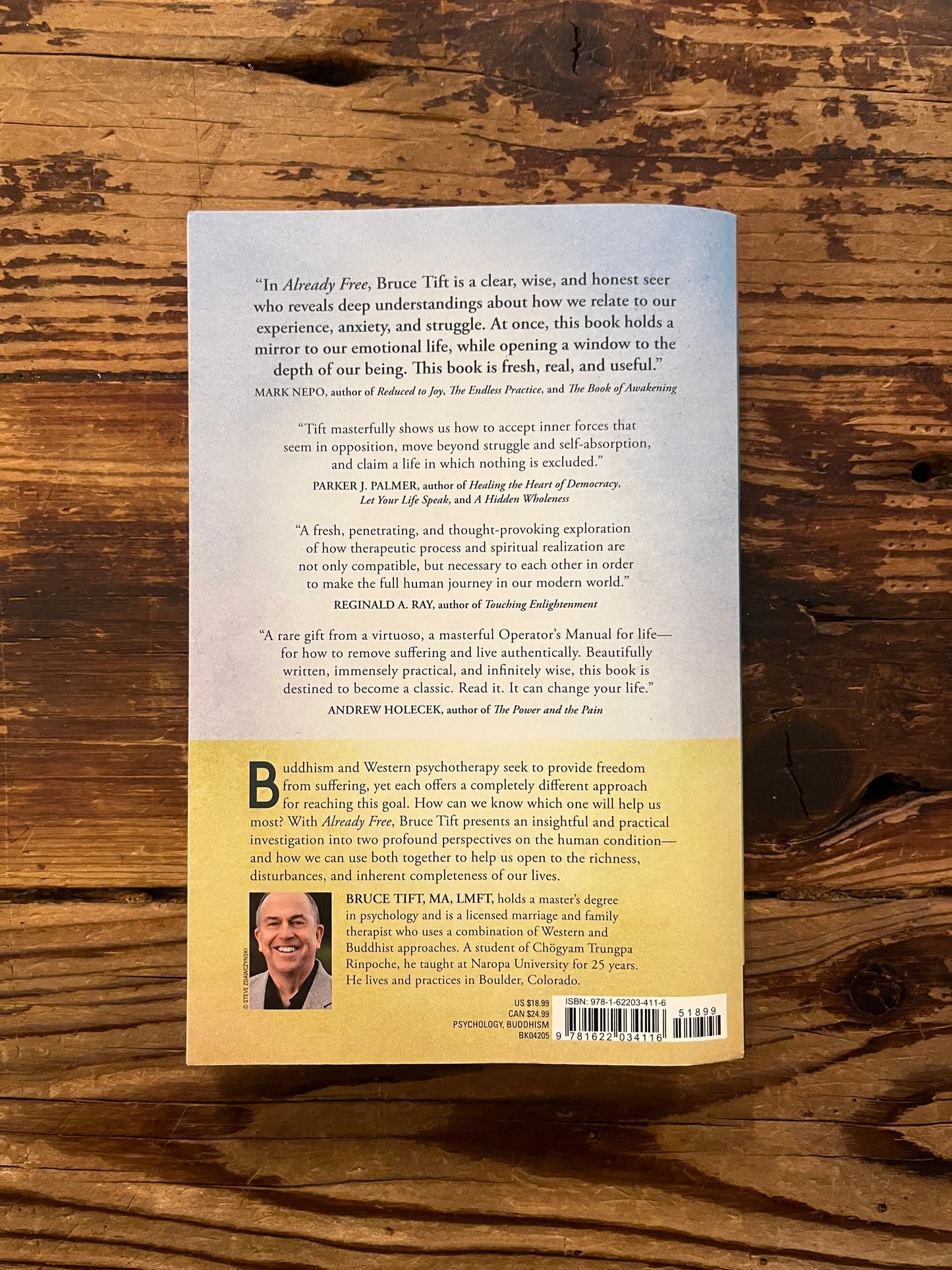 Backcover of book titled 'Already Free' by Bruce Tift on a wooden surface