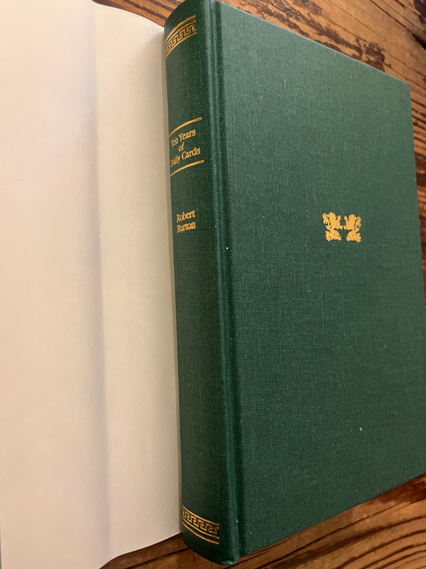 cover without dust jacket of book with the title 'Ten Years of Daily Cards' by Robert Burton on a wooden surface