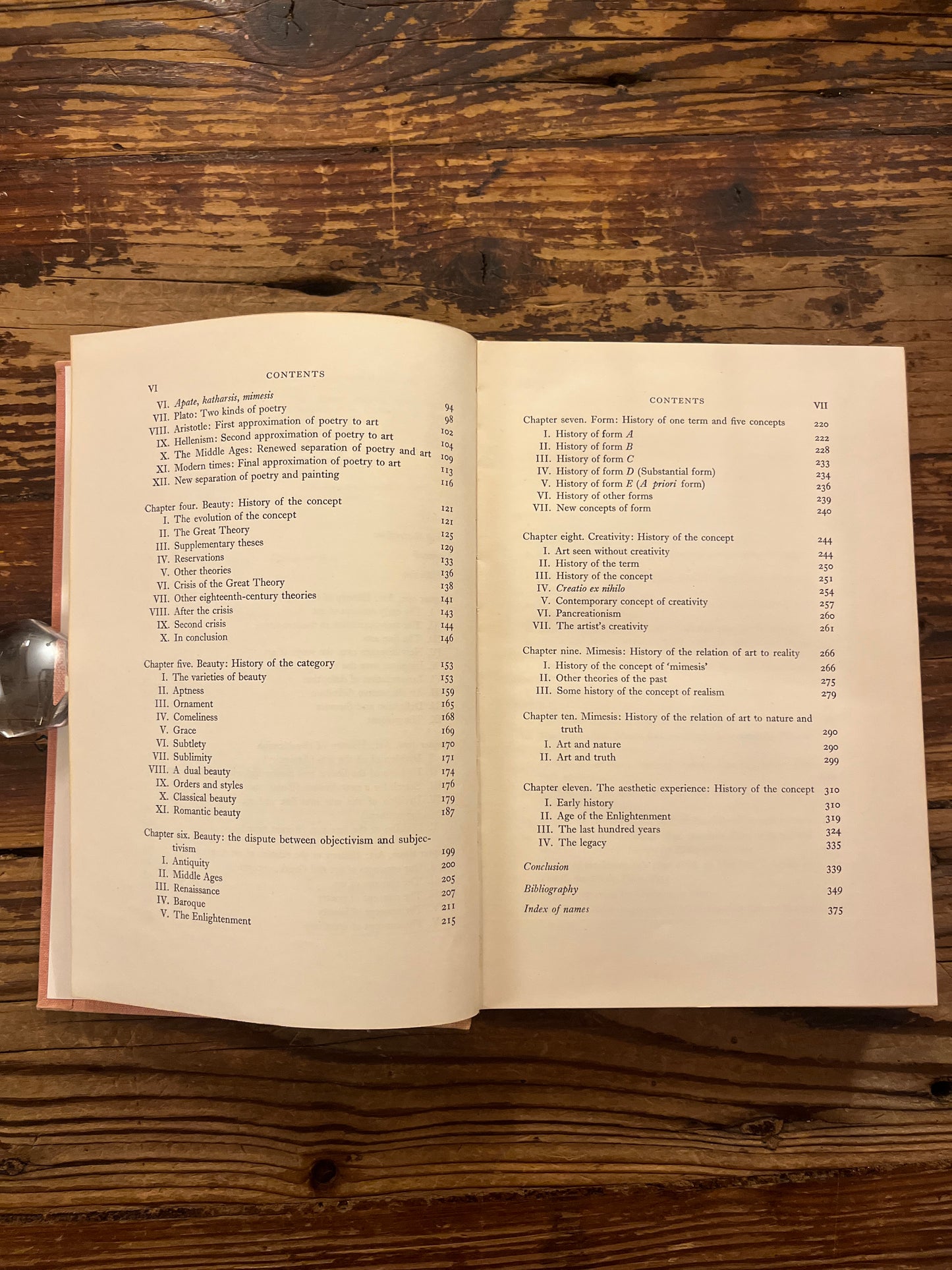 Pink book titled 'A History of Six Ideas' by Wladyslaw Tatarkiewicz on a wooden surface