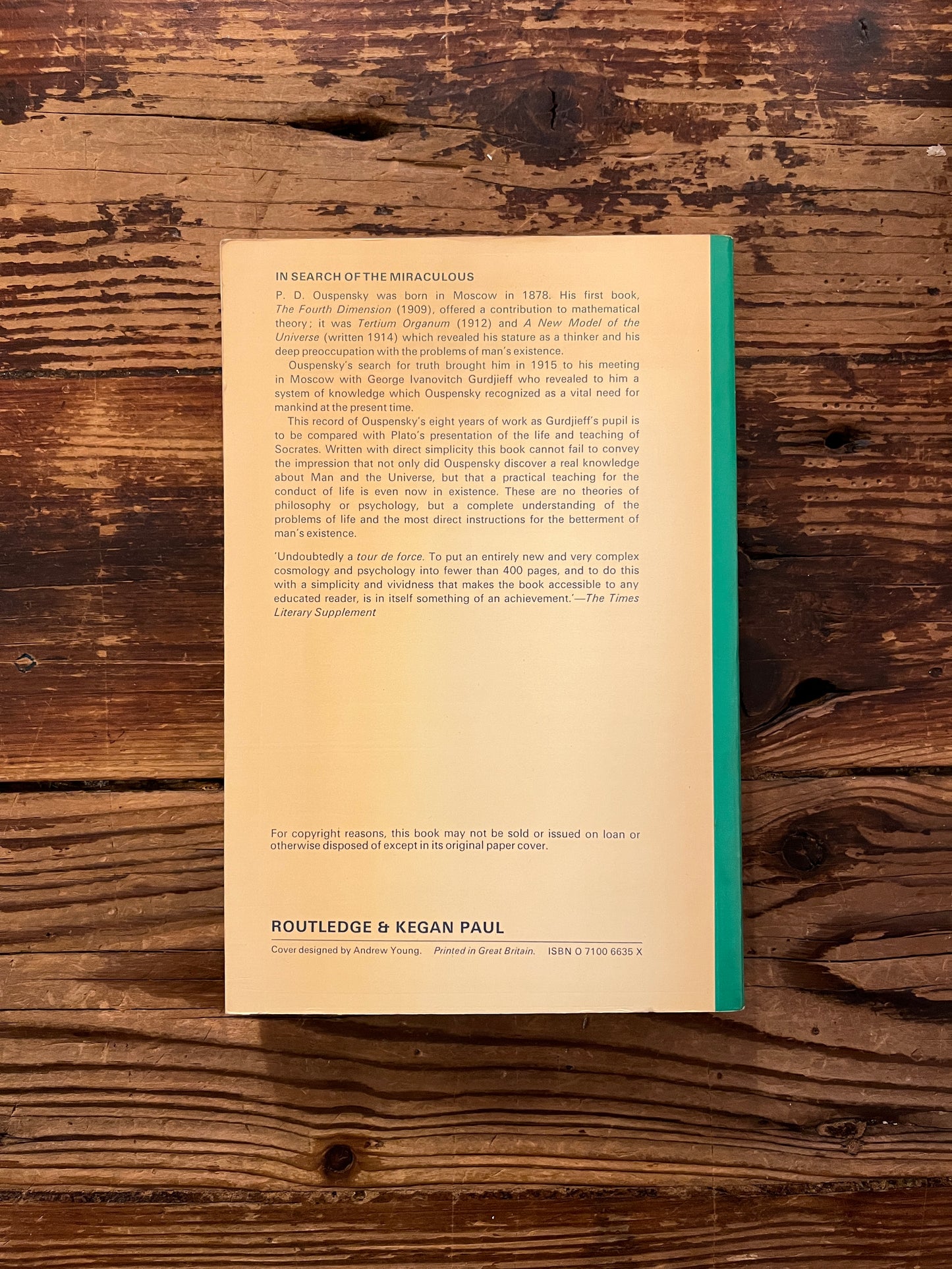 Back cover of book titled 'In Search of the Miraculous' by P.D. Ouspensky on a wooden surface
