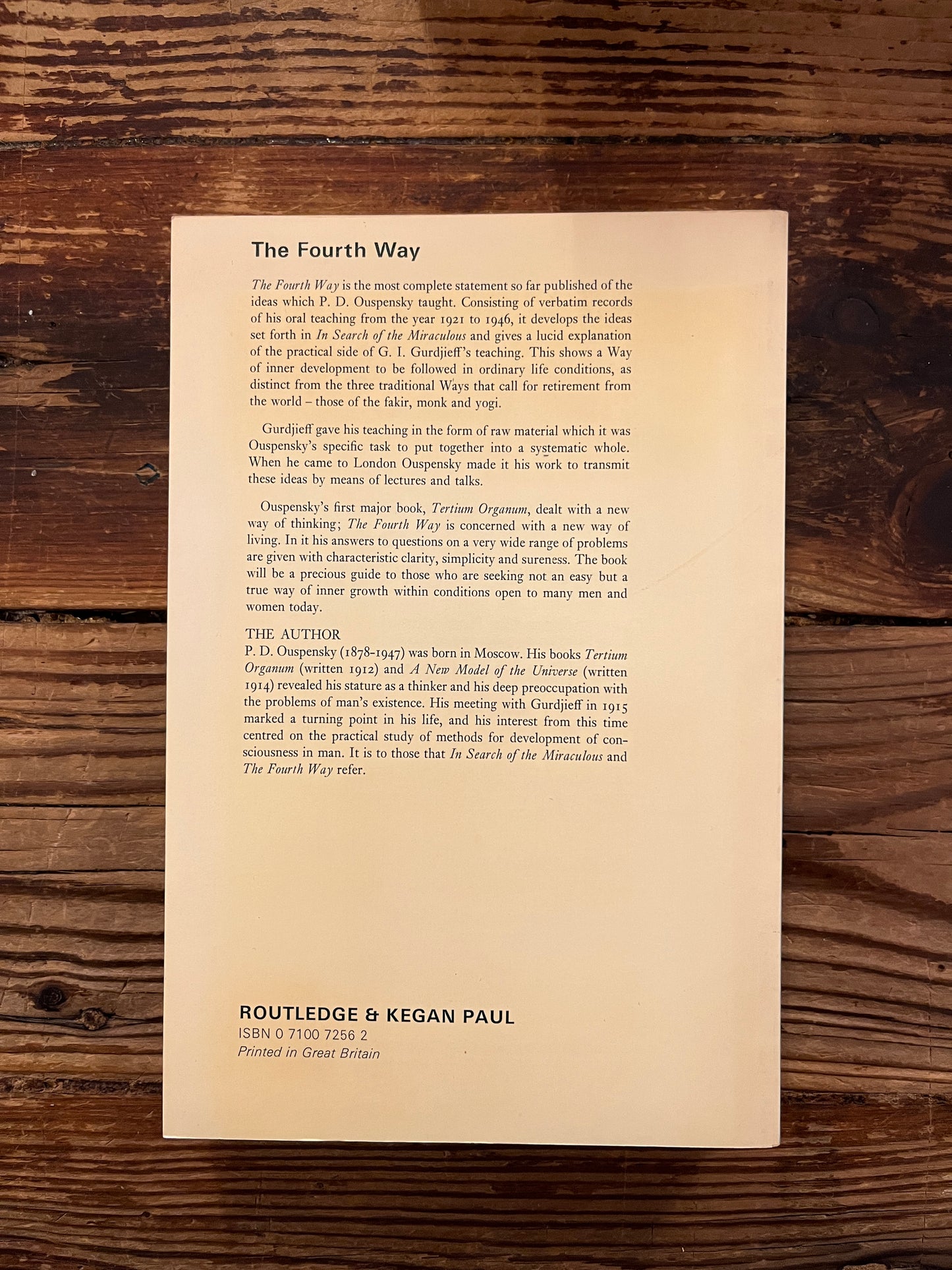 Back cover of a book with the title 'the fourth way' by P.D. Ouspensky on a wooden surface