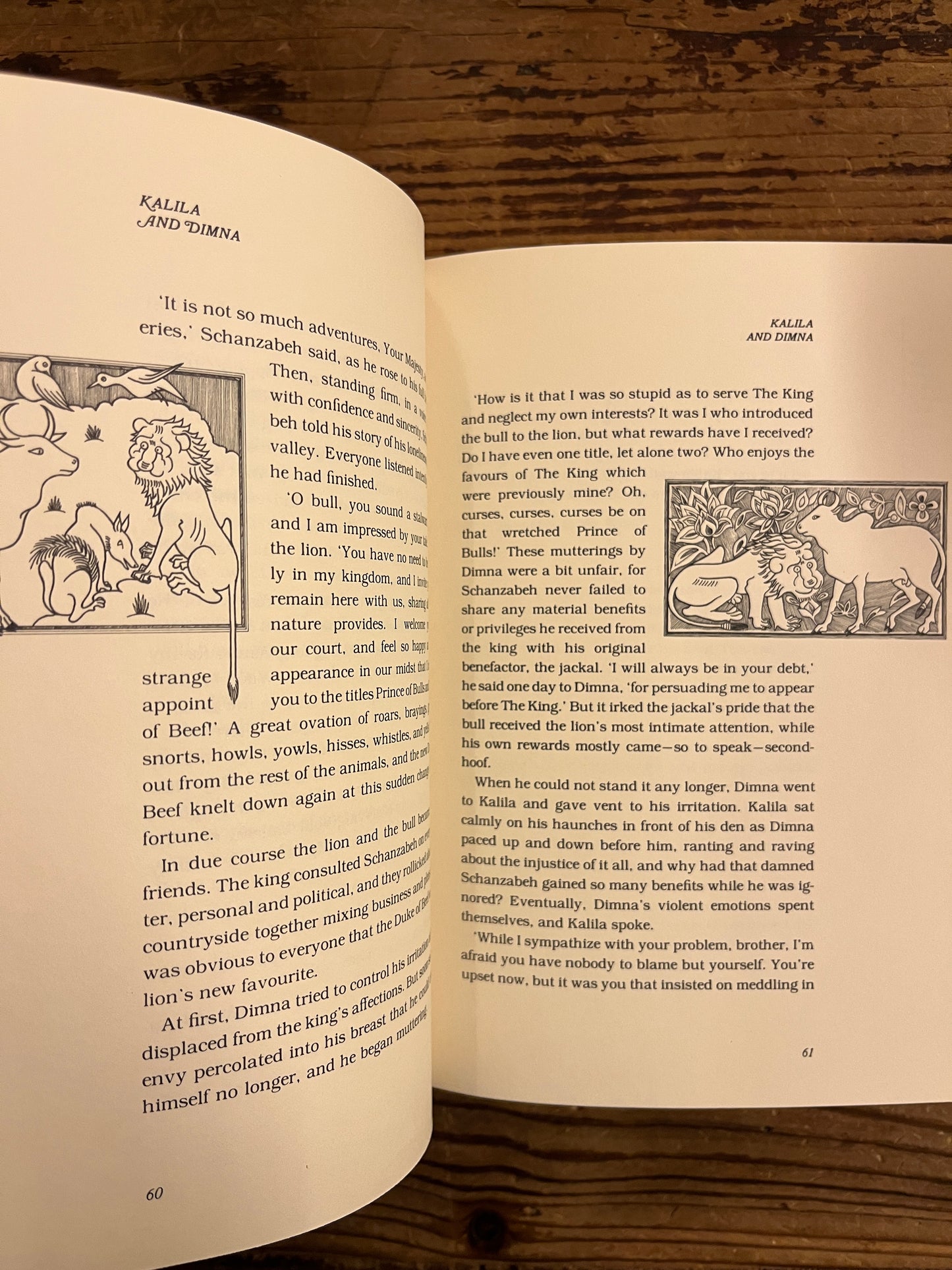 Open Book titled 'Kalila and Dimna, selected Fable of Bidpai' retold by Ramsay Wood on a wooden surface