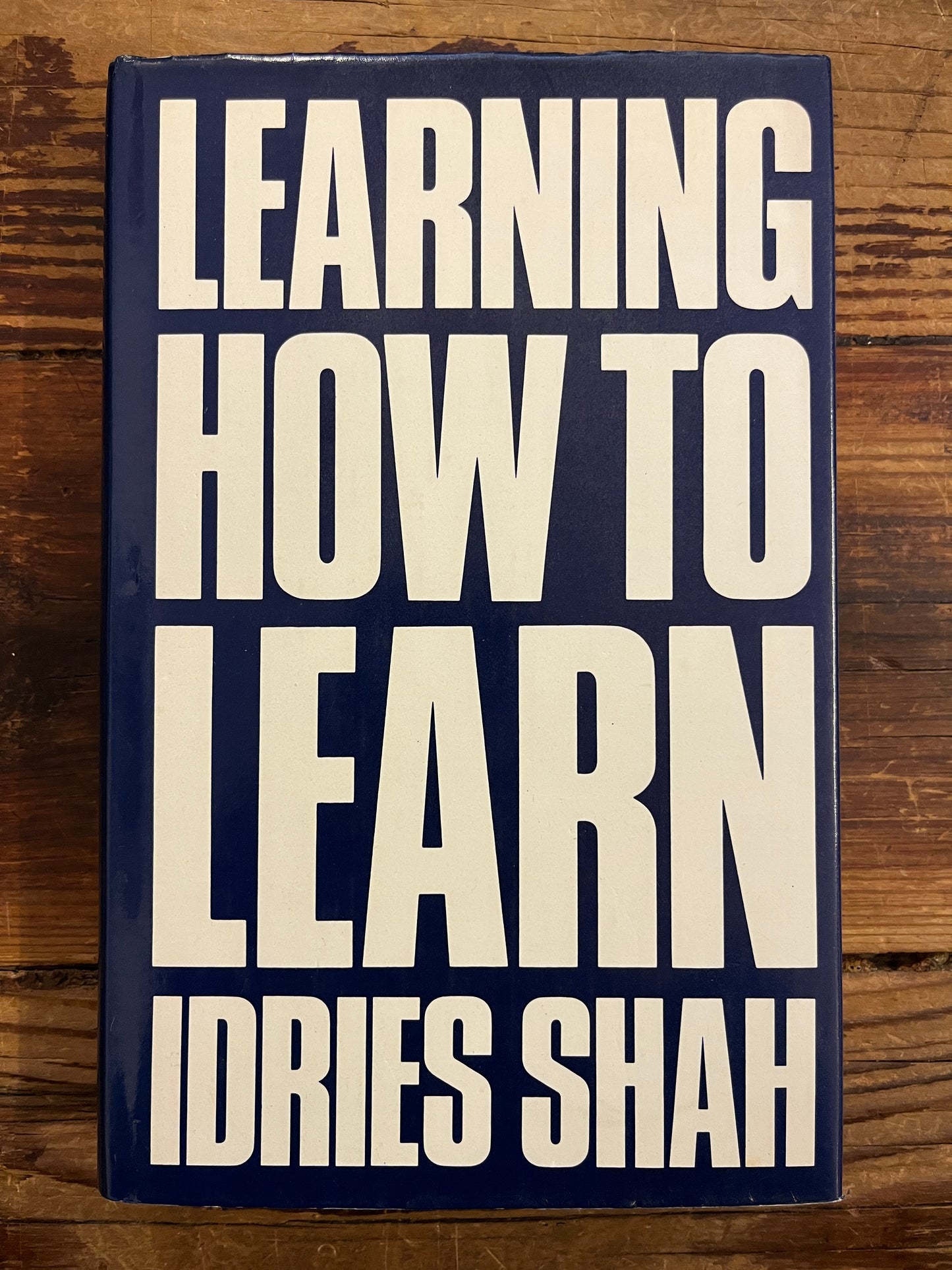Book titled 'Learning How to Learn' by Idries Shah on a wooden surface
