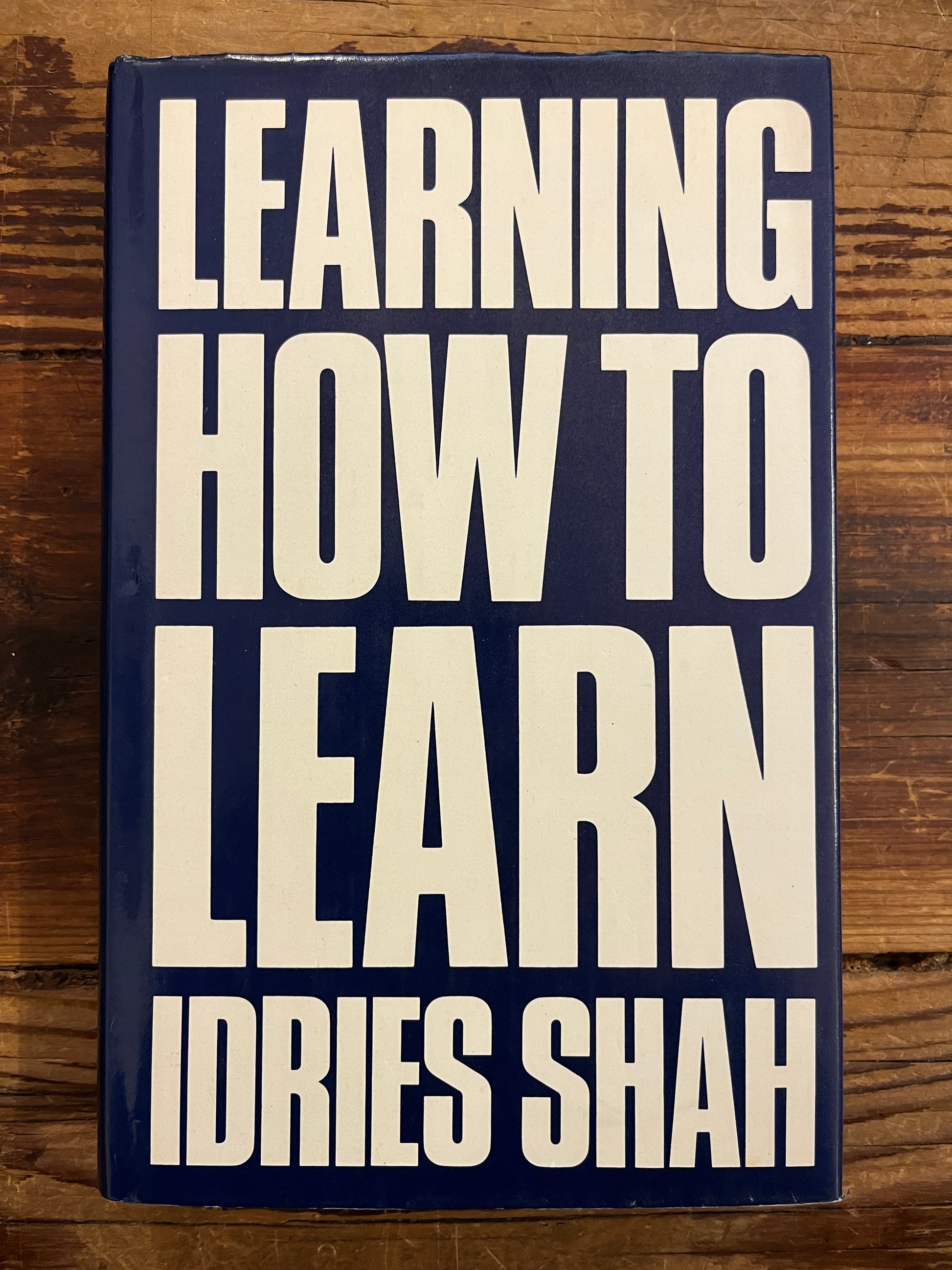 Book titled 'Learning How to Learn' by Idries Shah on a wooden surface