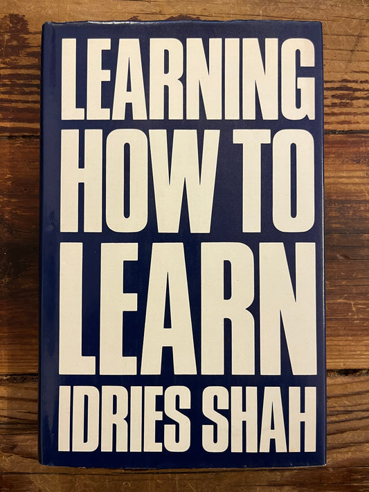Book titled 'Learning How to Learn' by Idries Shah on a wooden surface