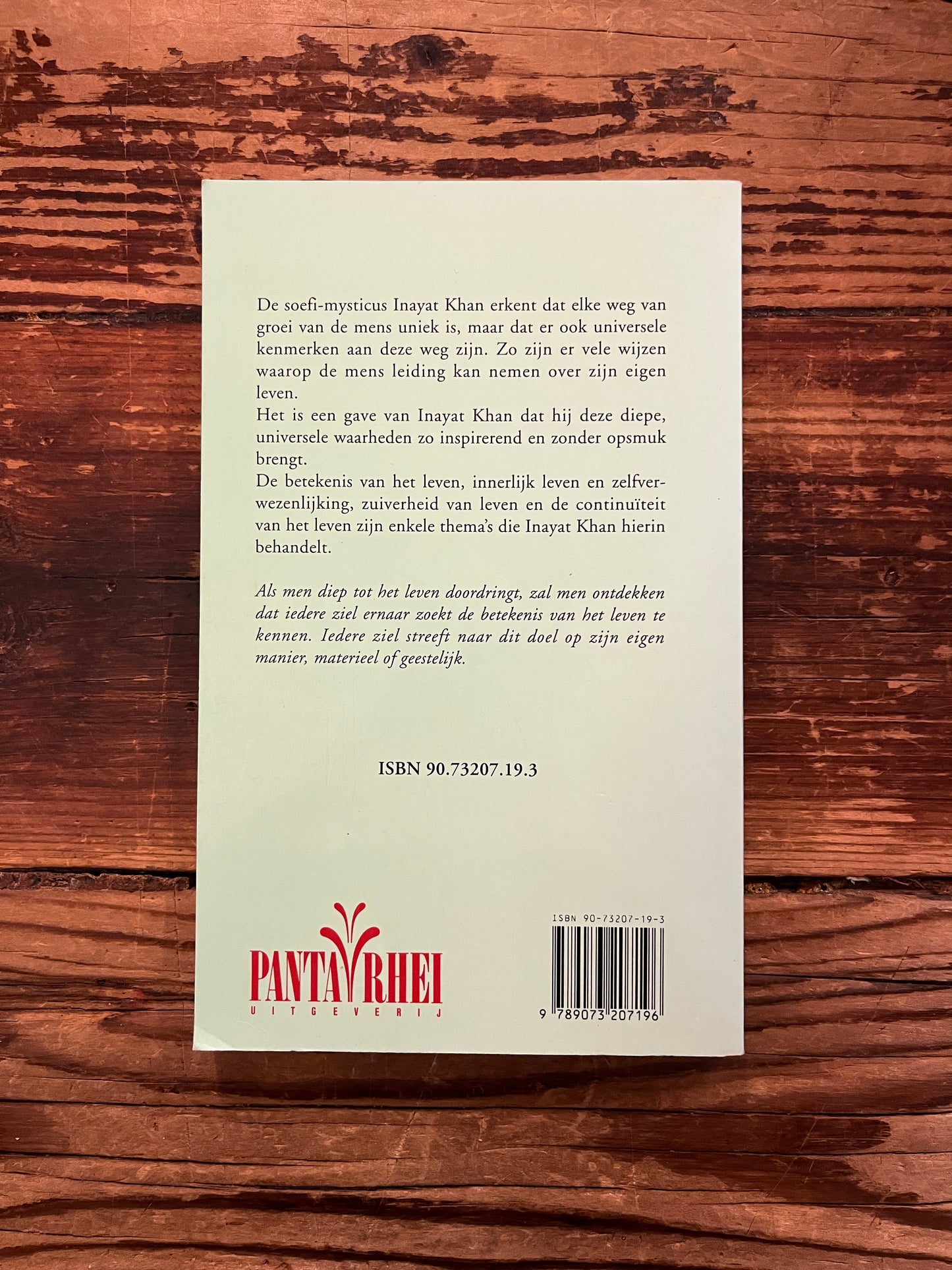 Achterkant van haar boek 'De mens, meester van zijn lot' by Inayat Khan op een houten achtergrond