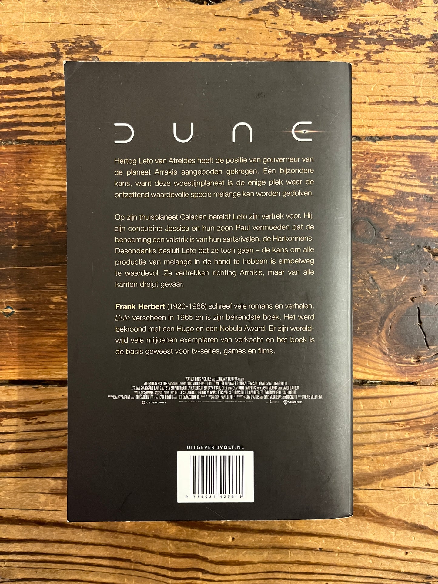 Achterkant van boek met de titel 'Dune' door Frank Herbert op een houten achtergrond