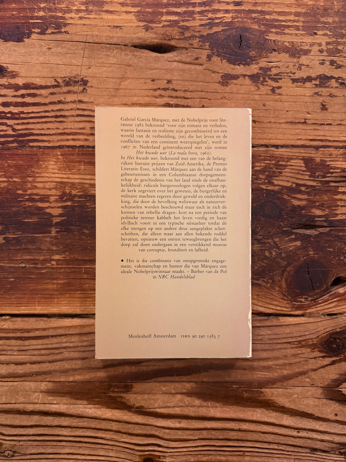 Achterkant van boek met de titel 'Het kwade uur' door Gabriel García Márquez op een houten achtergrond