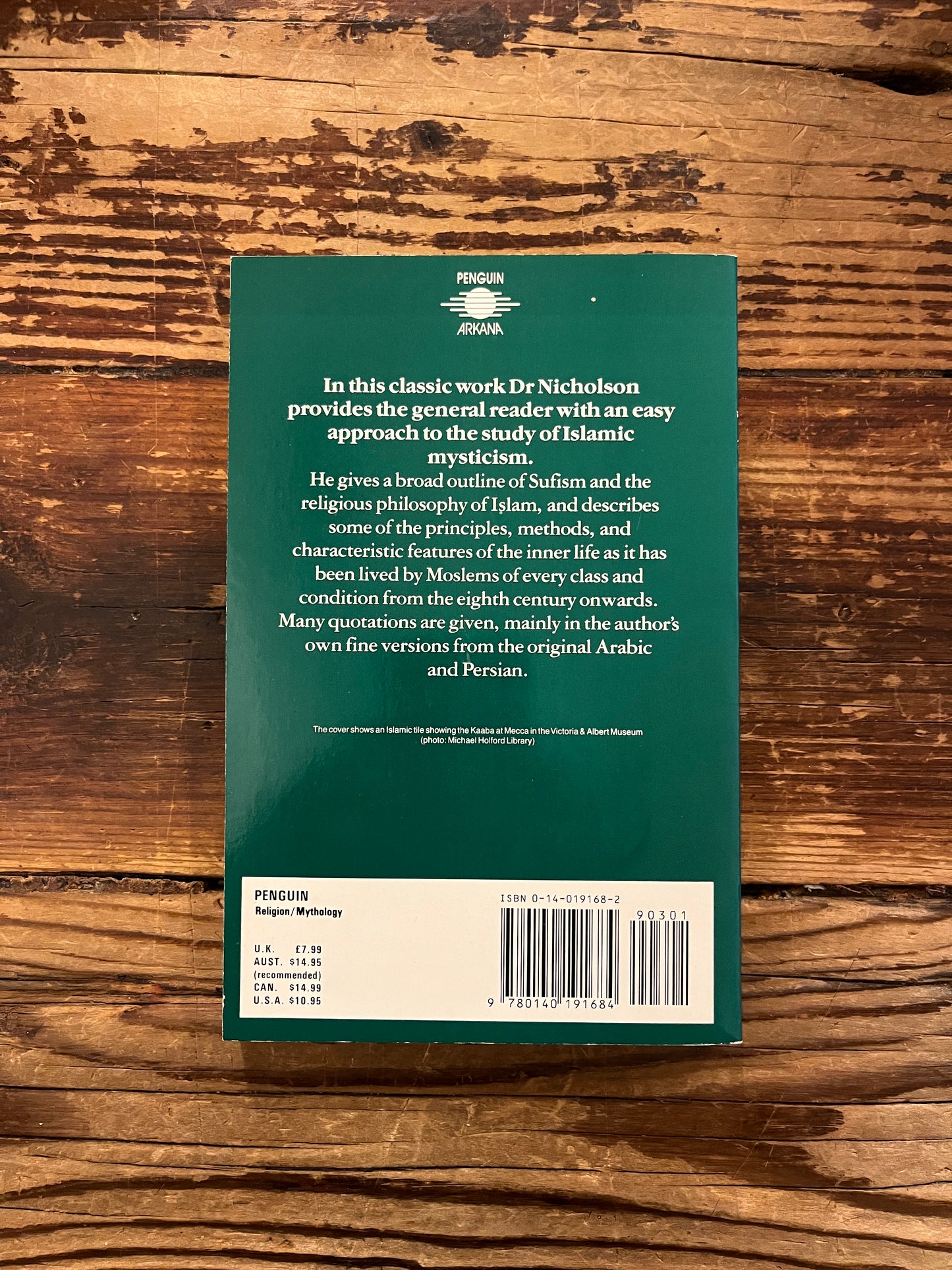 Back cover book titled 'The Mystics of Islam' by Reynold Nicholson on a wooden surface