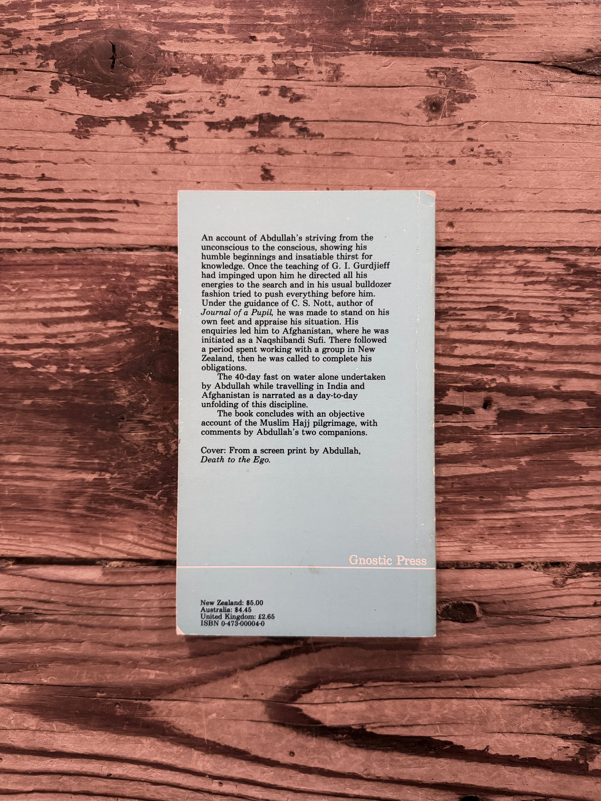 Back cover of a book with the title '40 days, an account of a discipline' by Abdullah Dougan on a wooden surface