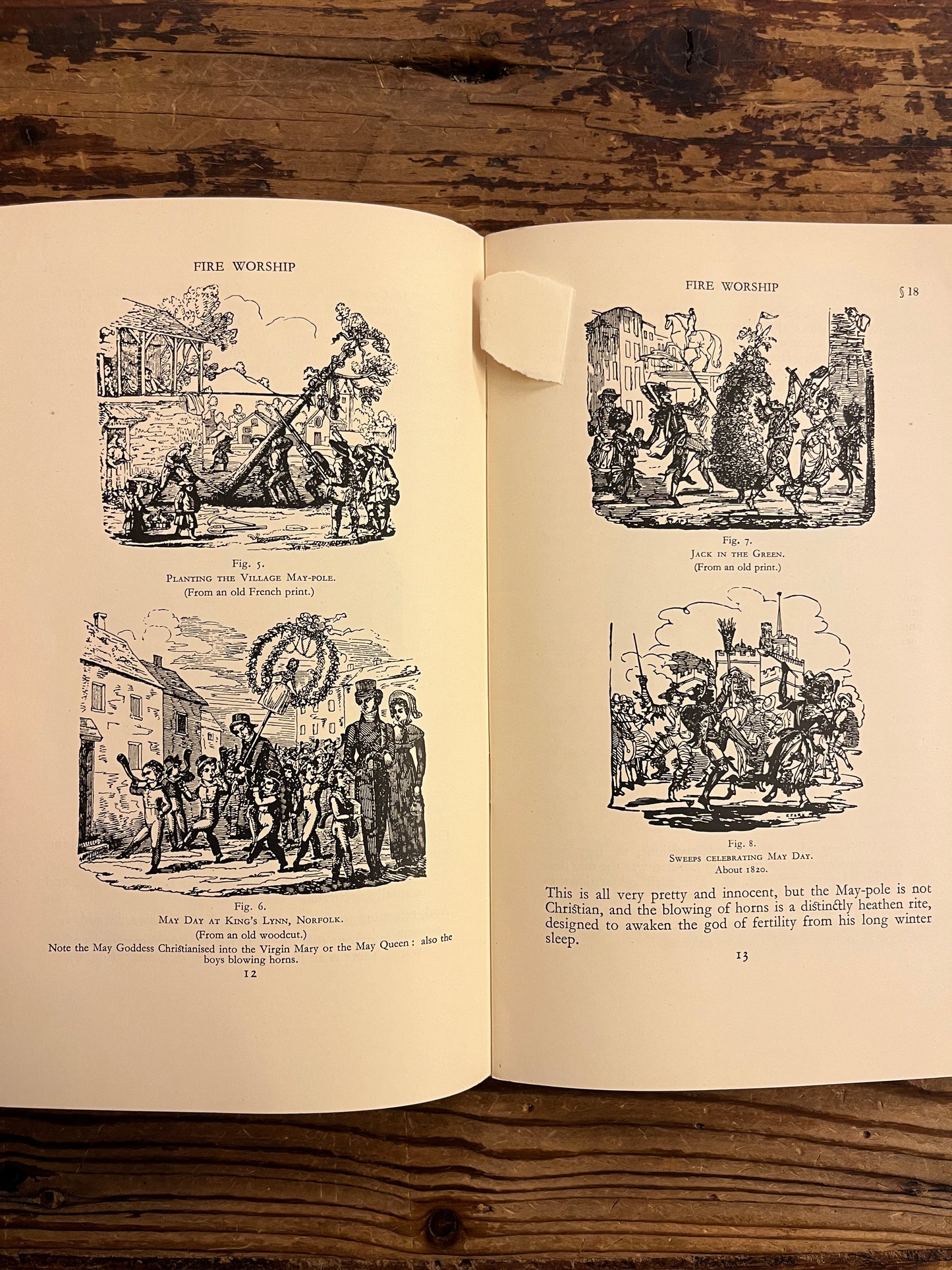 Open book with black and white illustrations on a wooden surface