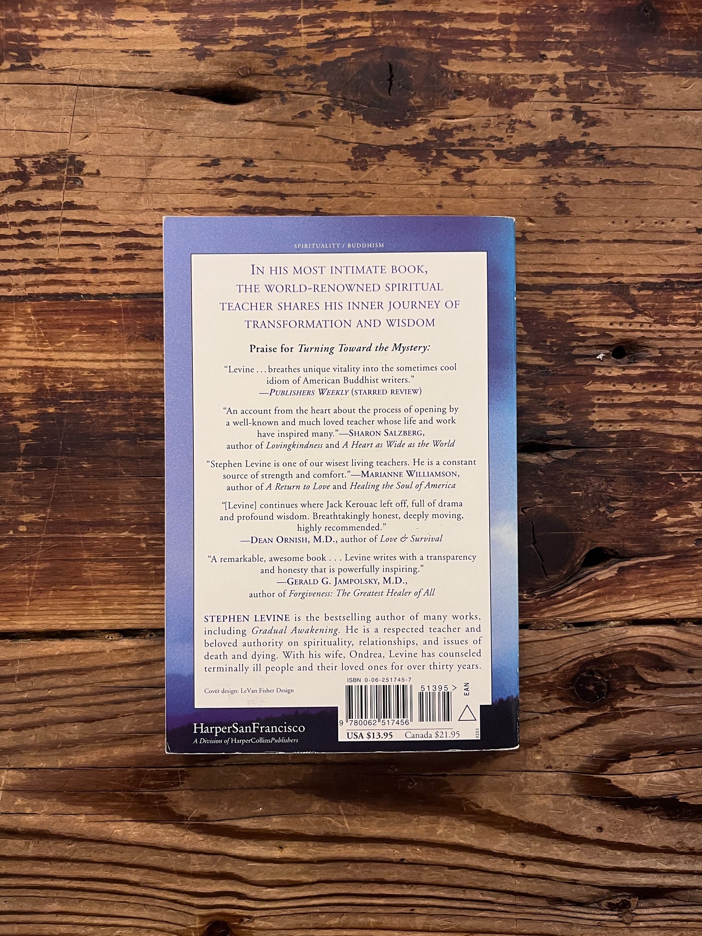 Book titled 'Turning Toward the Mystery' by Stephen Levine on a wooden surface