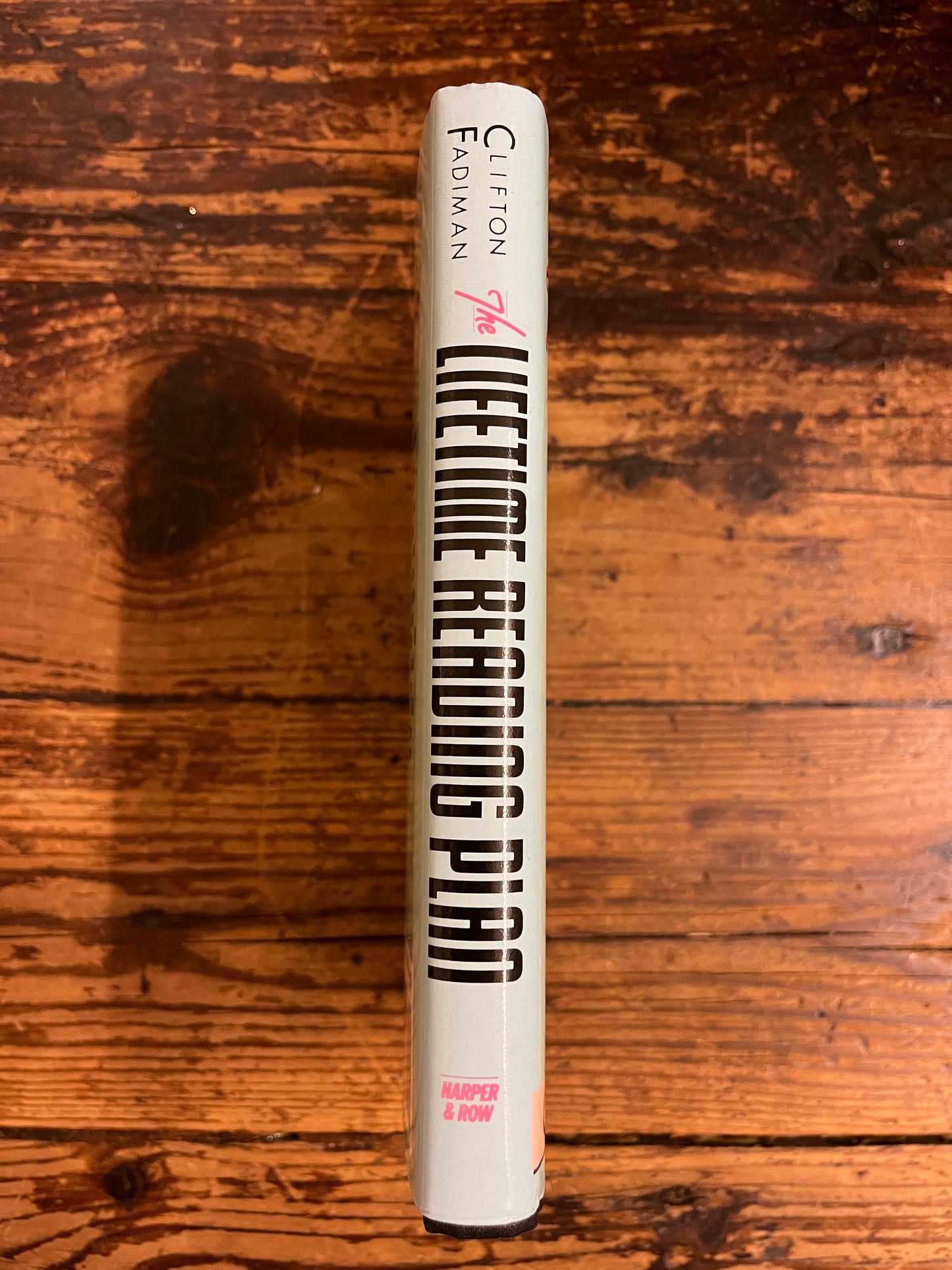 spine of the book "the lifetime reading plan"on a wooden background