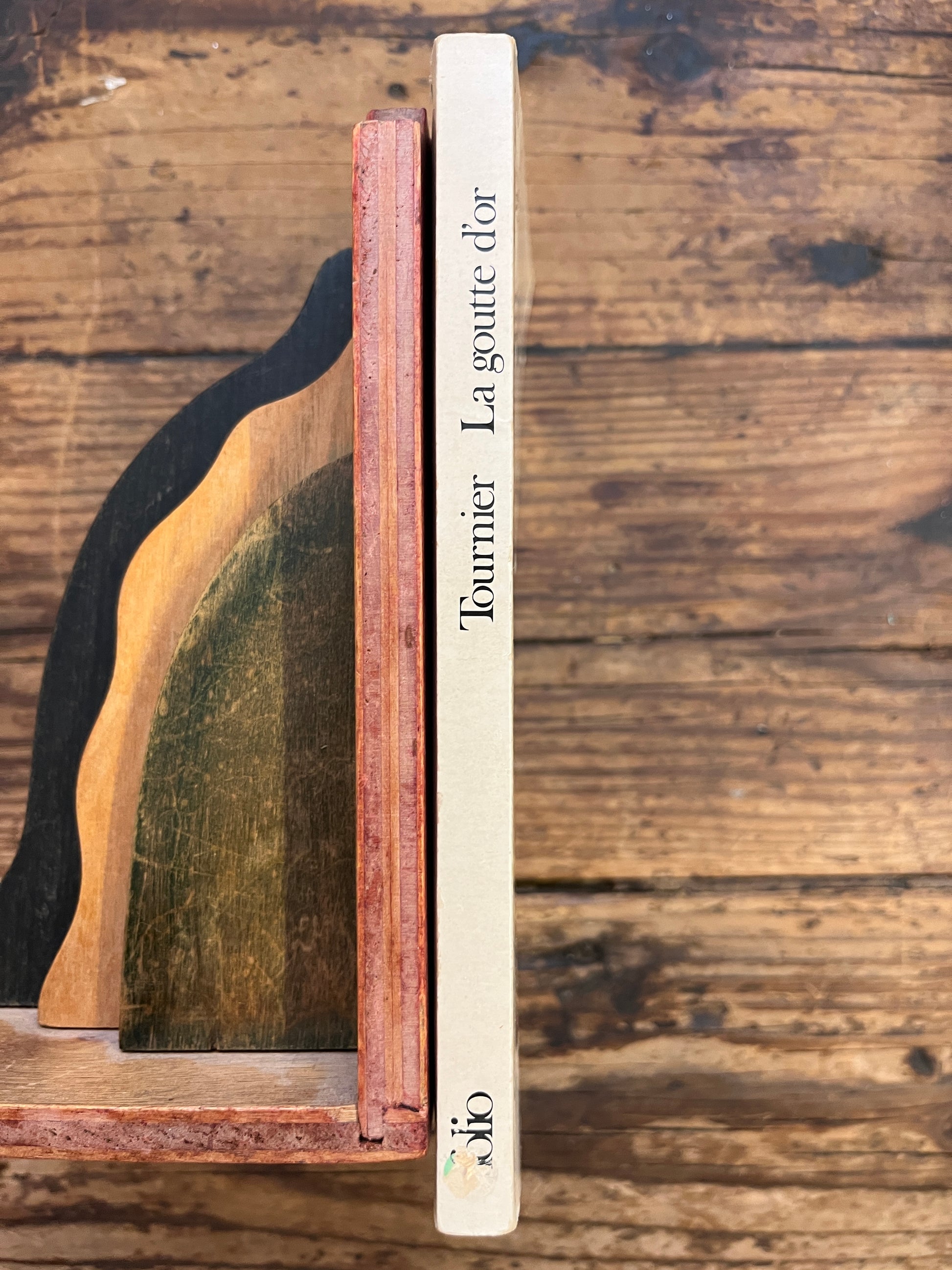 tranche du livre "la goutte d'or" de Michel Tournier aux editions Folio sur fond de bois