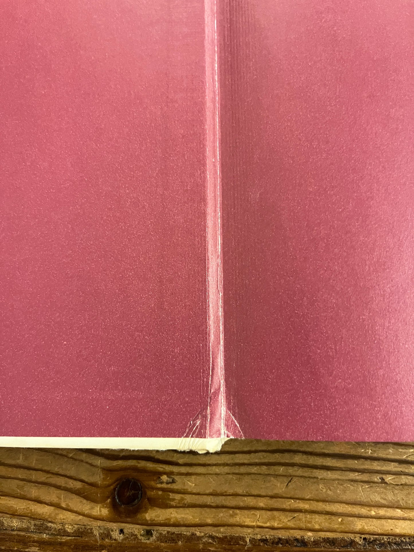 Close-up of a red book enterior showing light wear and tear on a wooden surface