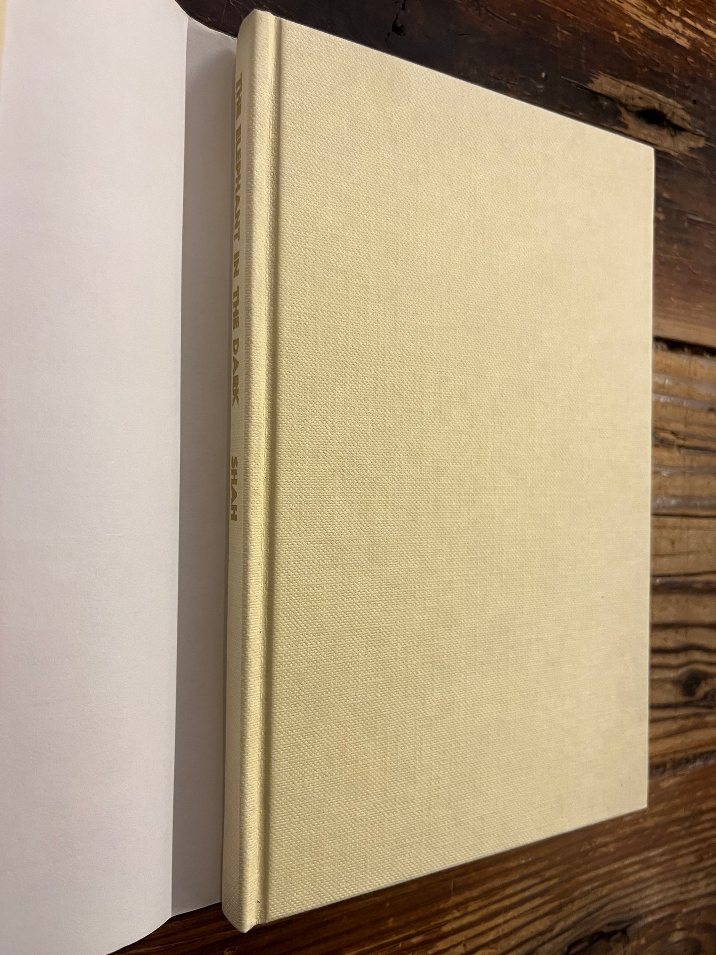 Beige book titled 'the elephant in the dark' by Idries Shahon a wooden surface