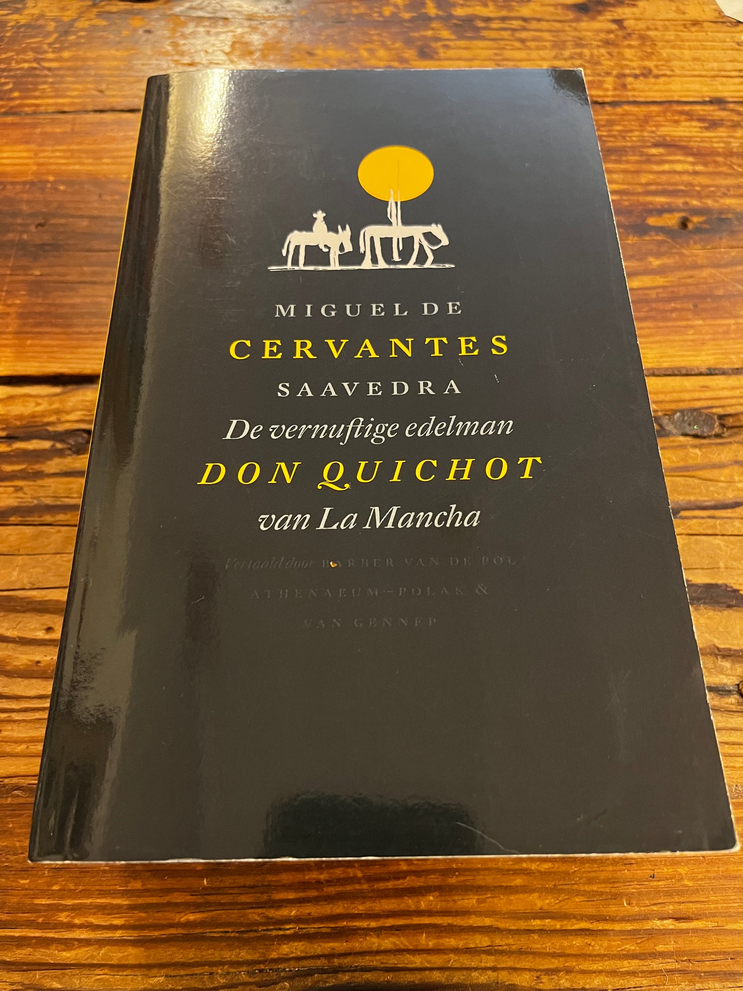 een boek met de titel 'Don Quichot' door Miguel de Cervantes op een houten achtergrond